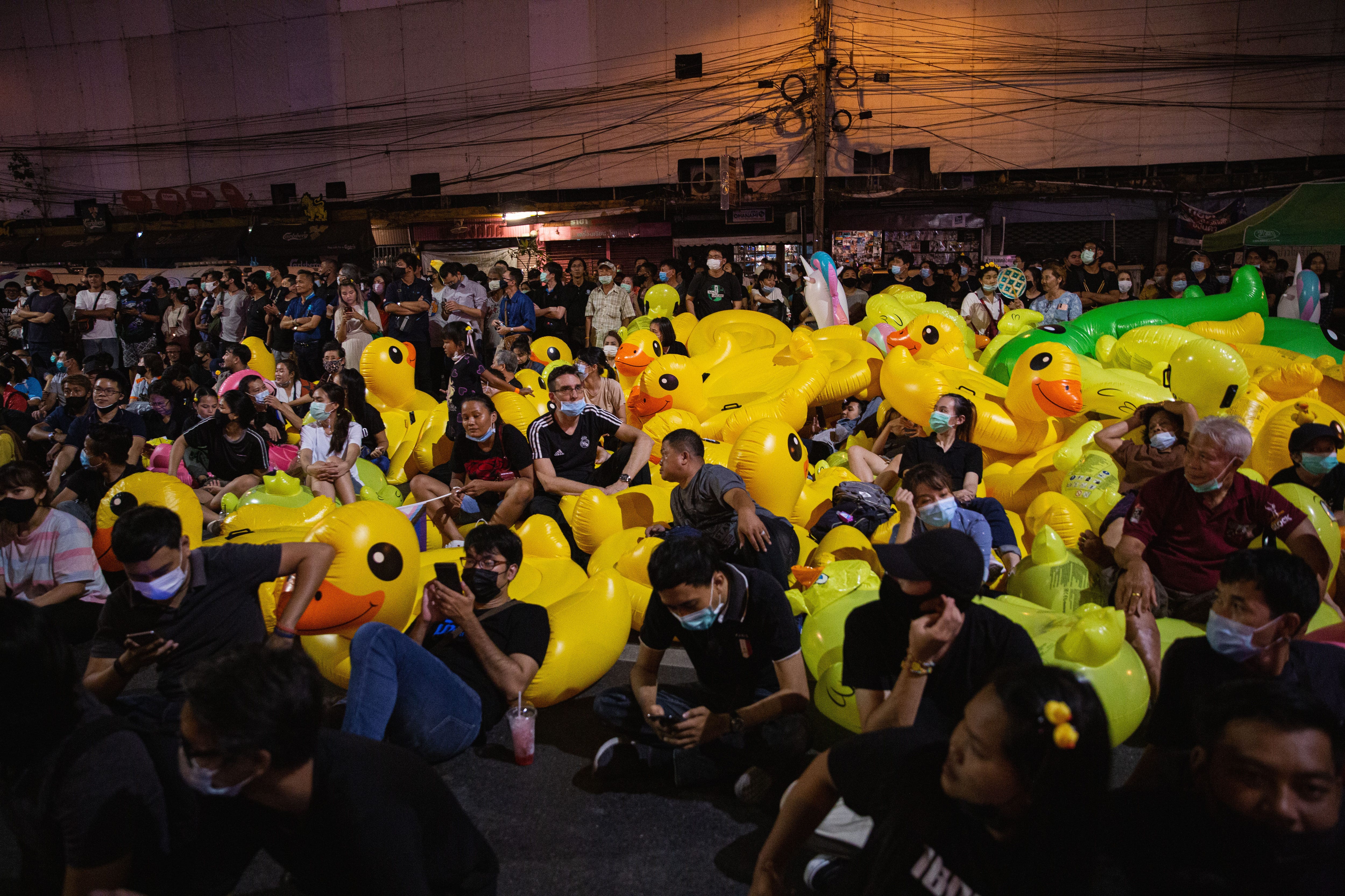 Demonstranten ruhen sich während einer Demonstration auf aufblasbaren Enten aus.