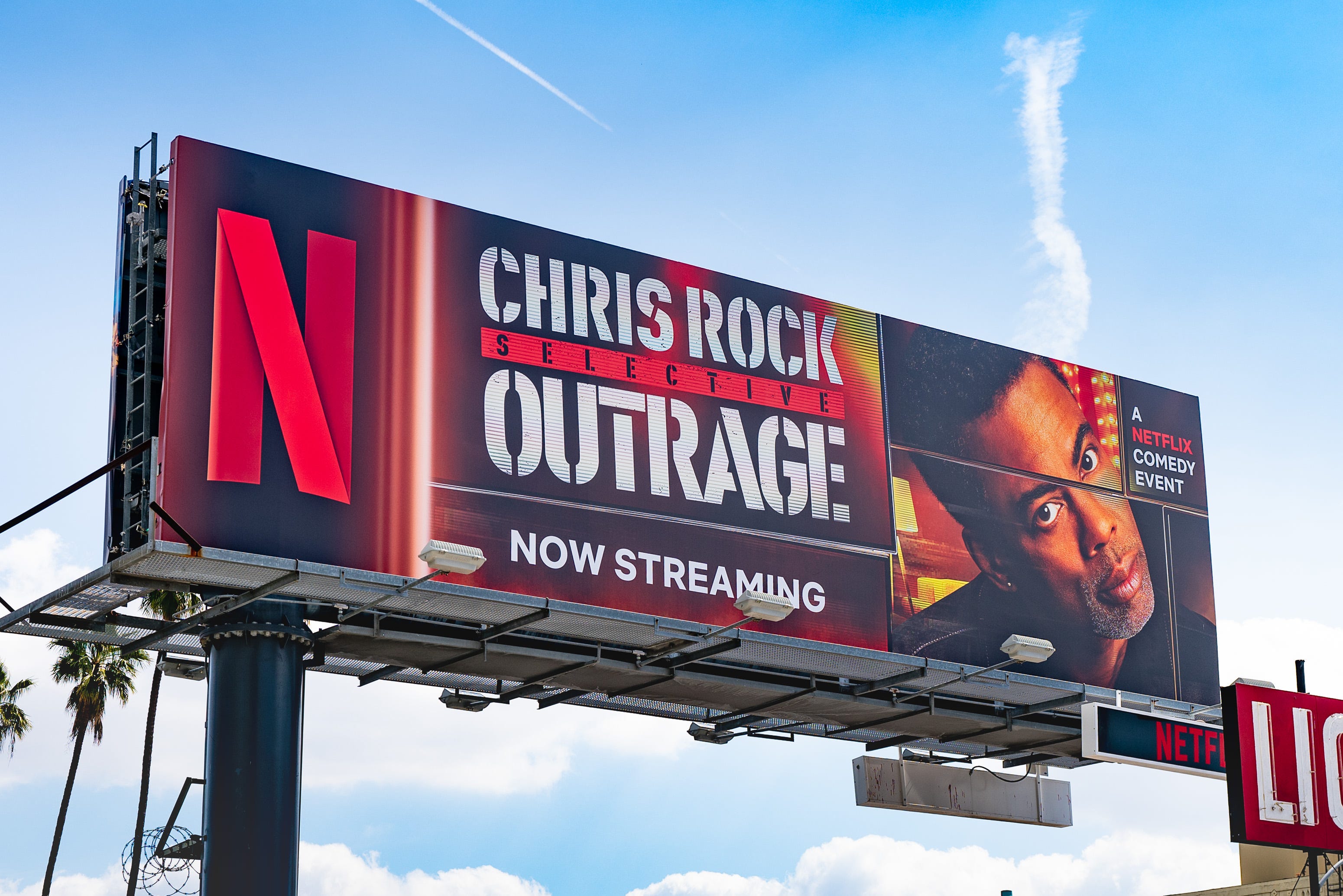 Eine Netflix-Plakatwand, die Chris Rocks Comedy-Special „Selective Outrage“ vor einem blauen Himmel mit weißen Wolken bewirbt.