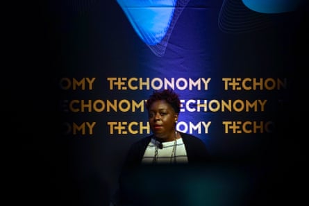 Frau spricht an einem Rednerpult, hinter ihr steht Technomy auf blauem Hintergrund.