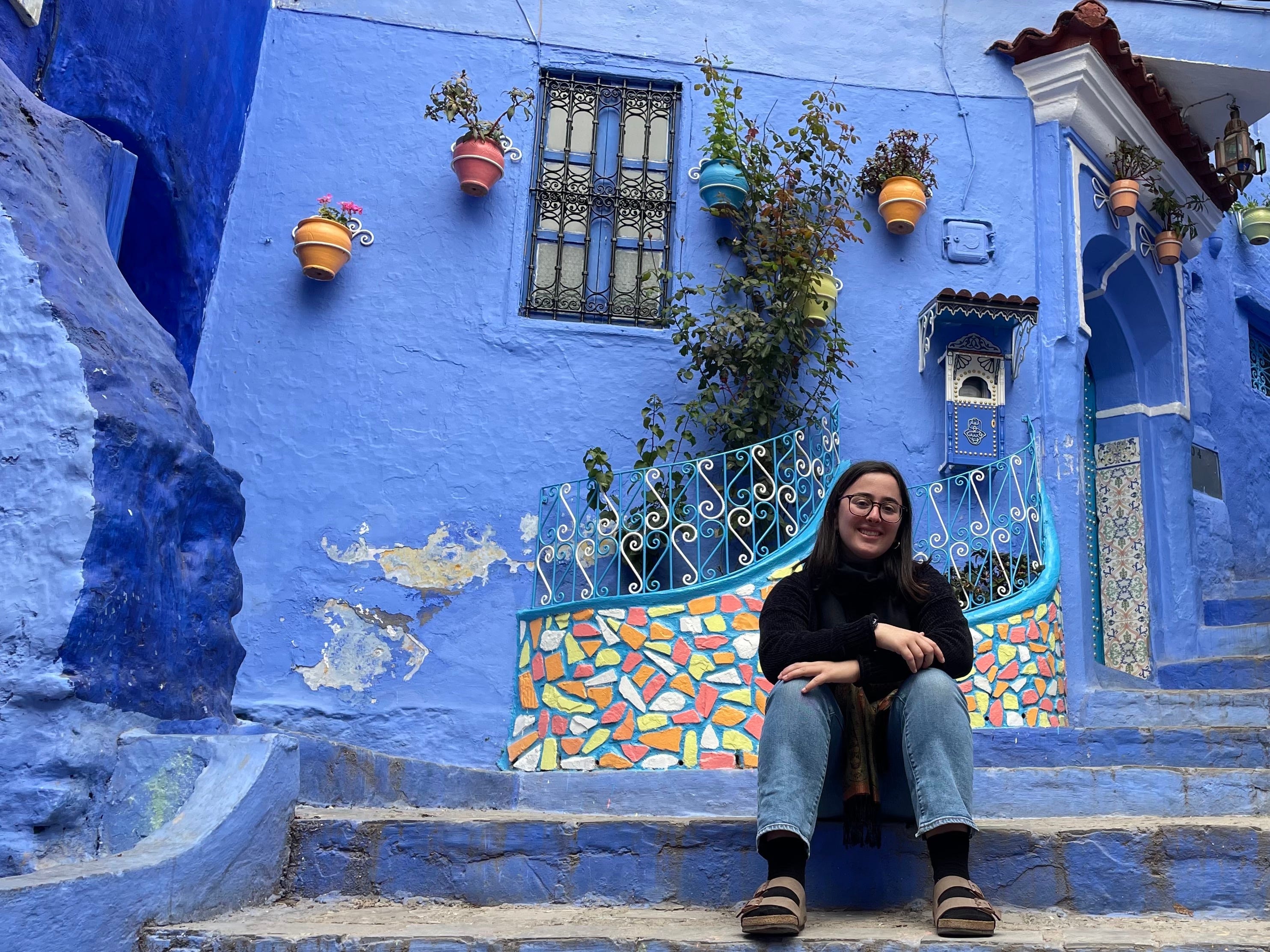 hannah sitzt vor einem blauen haus in marokko