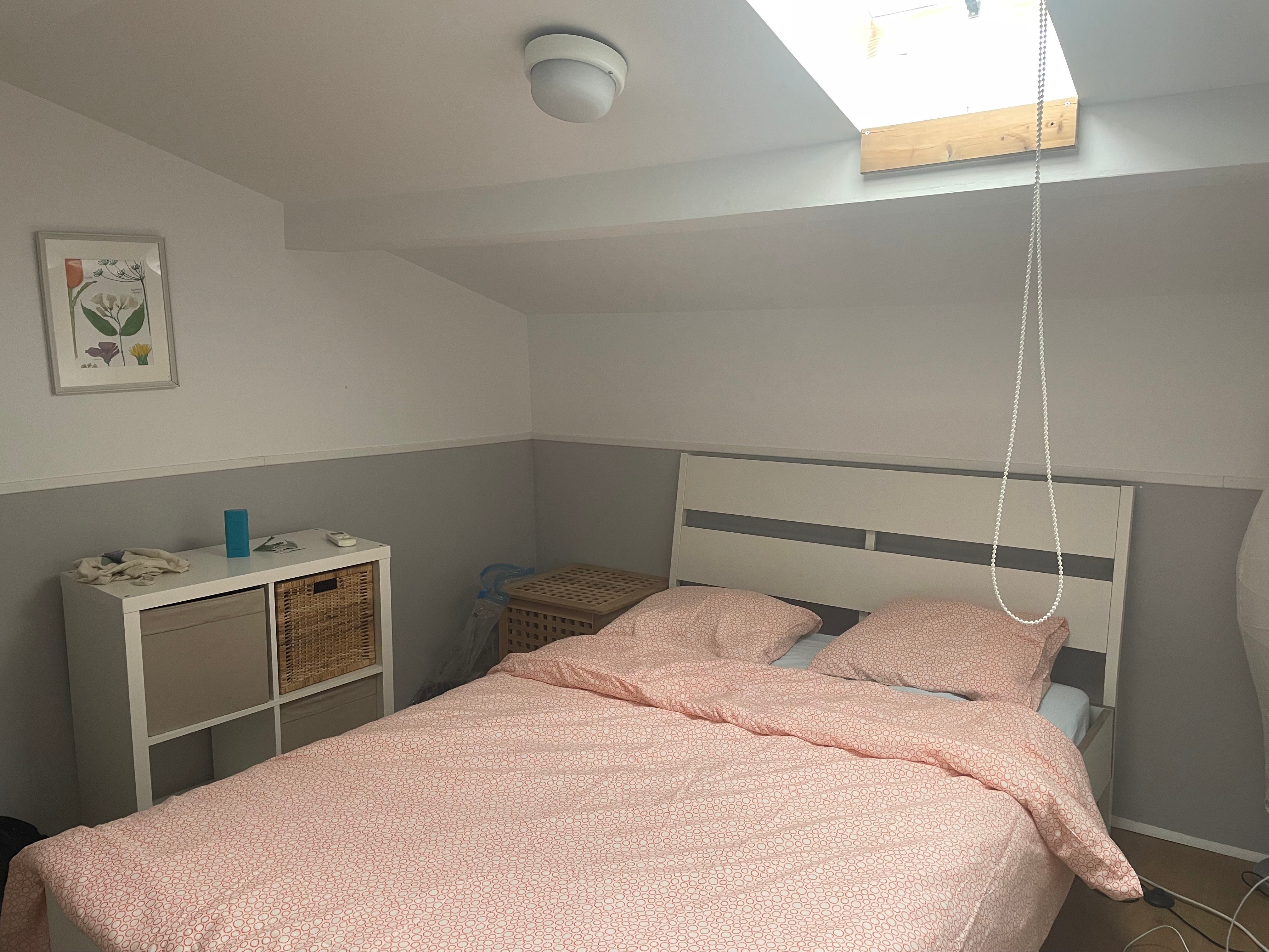 Foto eines kleinen Schlafzimmers in einem Airbnb mit einem rosa Bett und weißen Möbeln