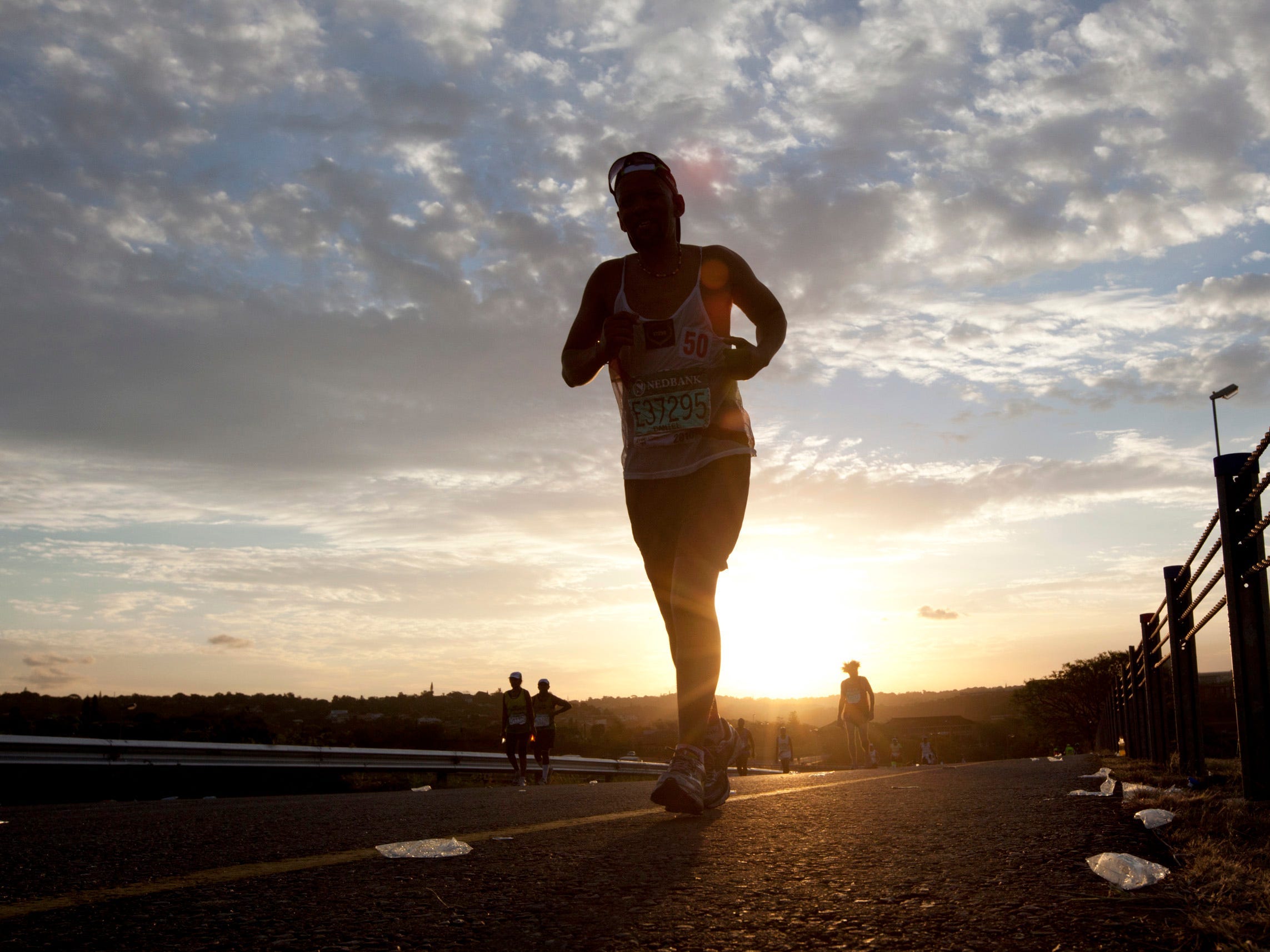 Ein Läufer ist auf einer Straße zu sehen, als die Sonne untergeht