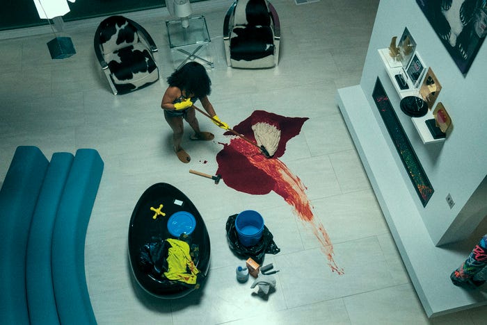 Dre (Dominique Fishback) wischt in diesem Standbild aus „Swarm“ in einem eleganten weißen Wohnzimmer Blut auf.