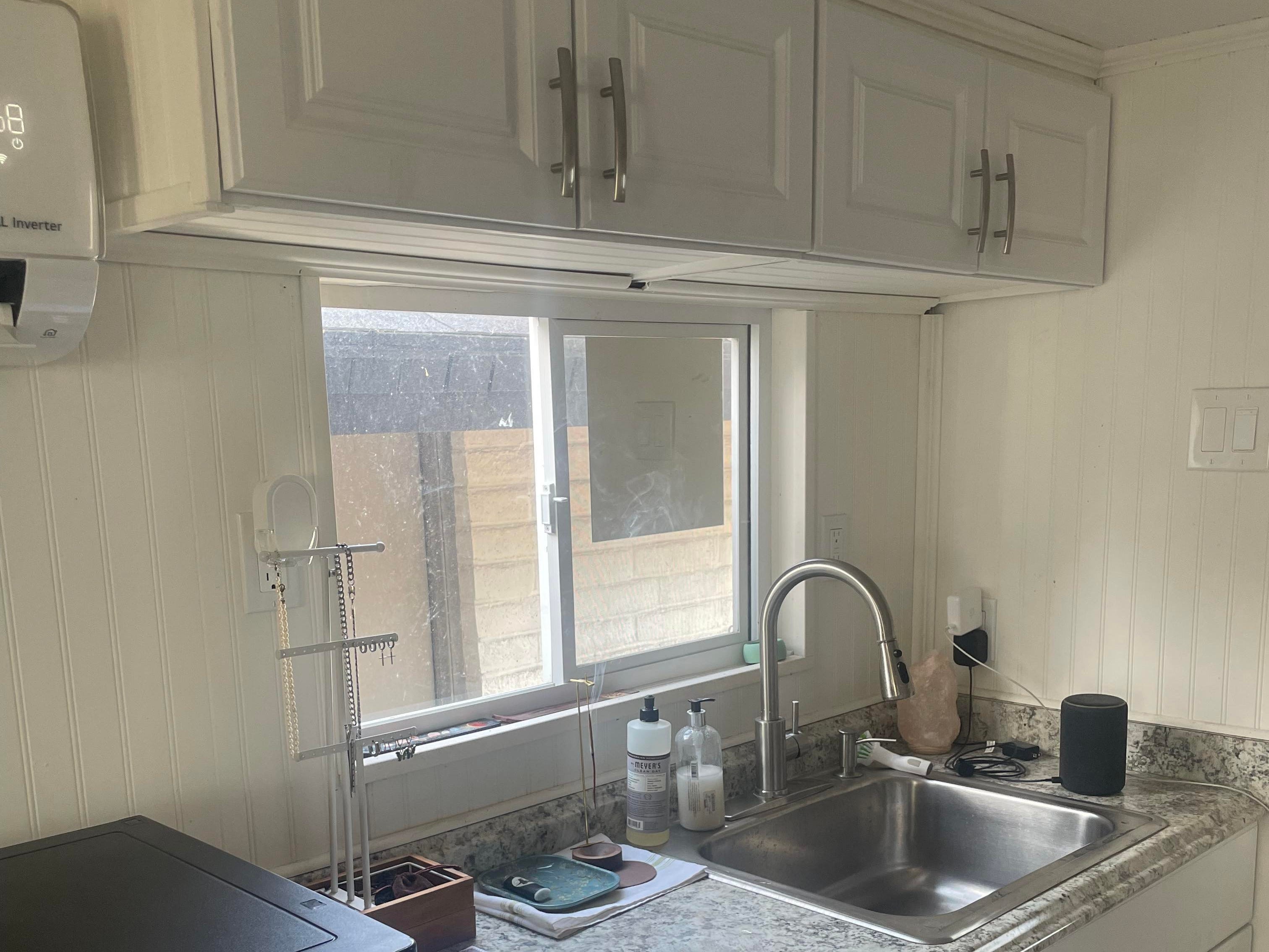 Der Küchenbereich im winzigen Haus mit weißen Schränken und einer grauen Arbeitsplatte
