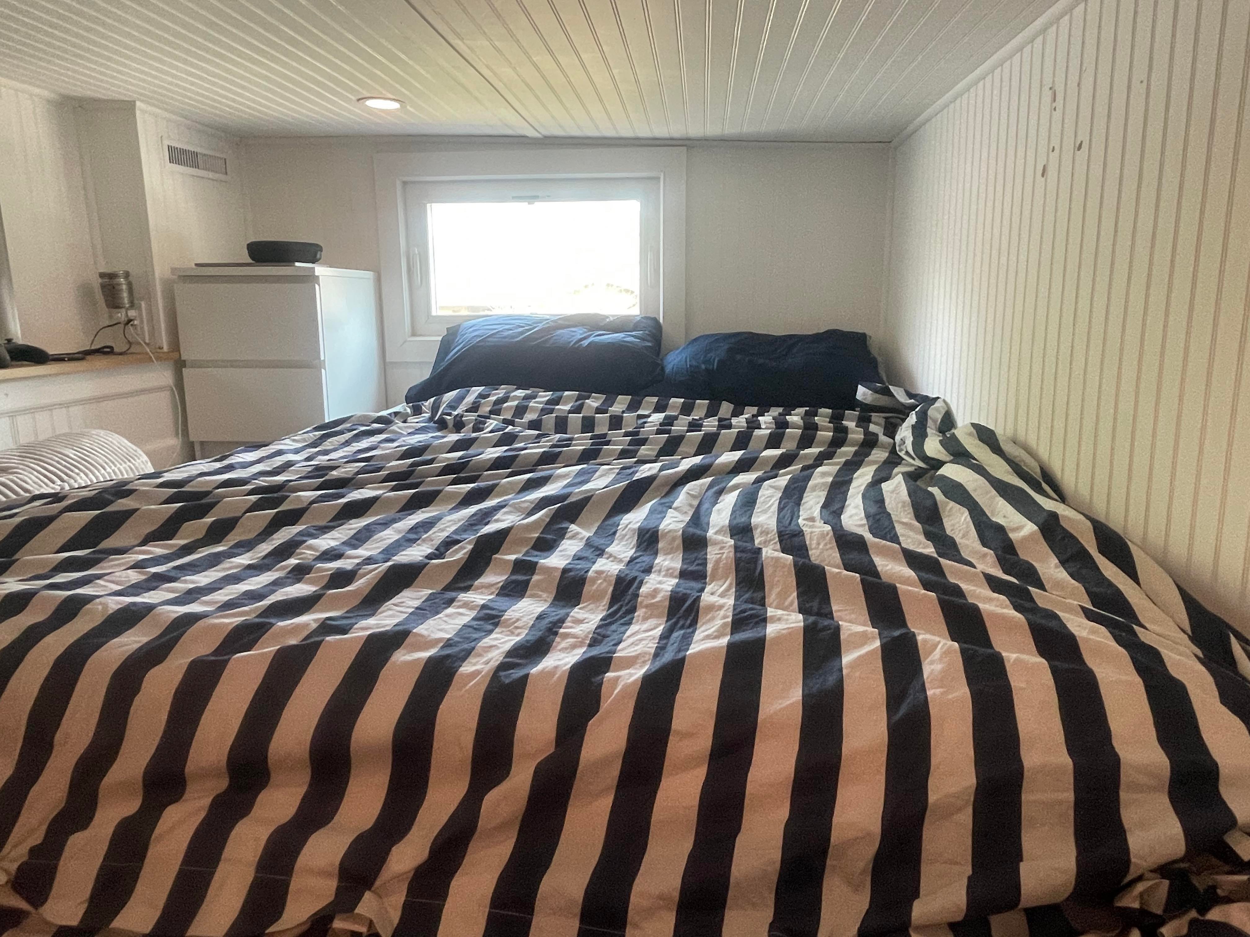 Ein Bett mit einer marineblau-weiß gestreiften Bettdecke