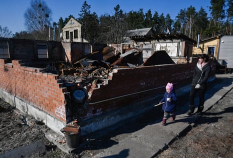 Eine Bewohnerin und ihr Kind gehen in der Nähe eines durch russischen Beschuss zerstörten Hauses im Dorf Moshchun spazieren.