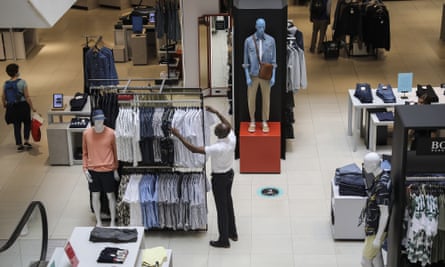 Ein Mitarbeiter arrangiert Kleidung in einem John-Lewis-Laden. 