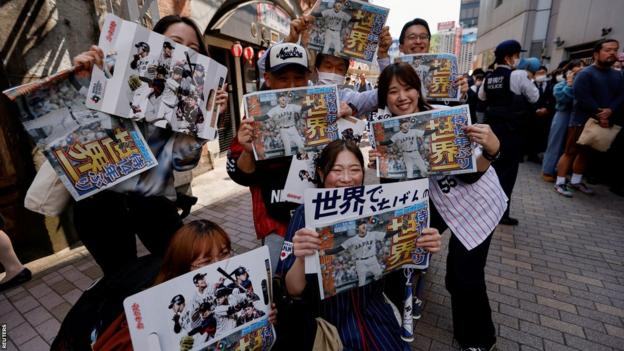Fans halten Sonderausgaben von Zeitungen in den Händen, die über Japans World Baseball Classic-Sieg berichten