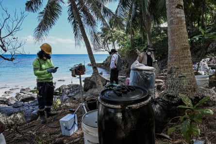 Menschen in chemischen Gasmasken halten Instrumente, während sie am Strand von Buhay na Tubig Messungen vornehmen