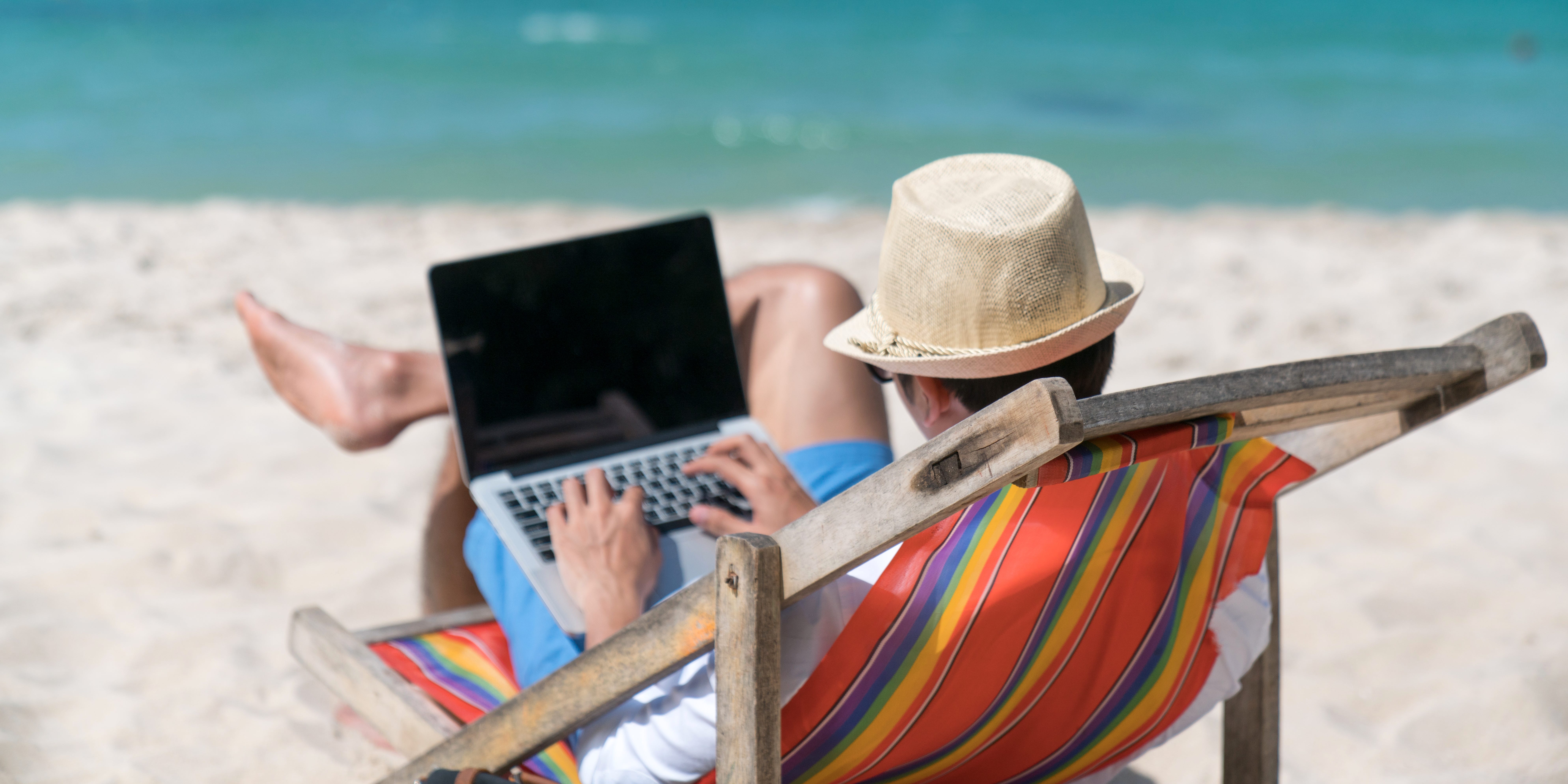 Eine Person auf einem Laptop am Strand