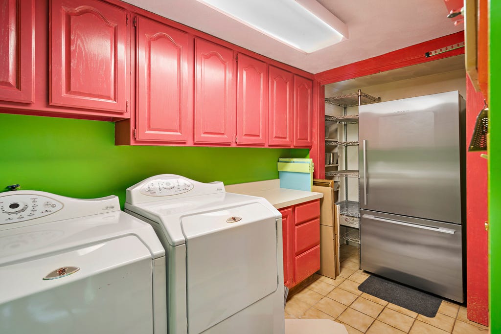 Eine Waschküche mit Kühlschrank und grünen Wänden