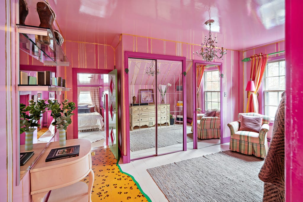 Ein Ankleidezimmer mit rosa und goldenen Wänden und verspiegelten Schranktüren
