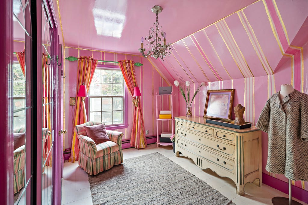 Ein Ankleidezimmer mit rosa und goldenen Wänden und einer glänzend rosa Decke