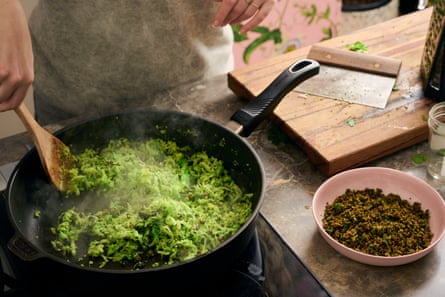 Geriebener Brokkoli wird in einer Pfanne angebraten;  Der Rand einer Schüssel mit gerösteten Semmelbröseln und Brokkoli. 