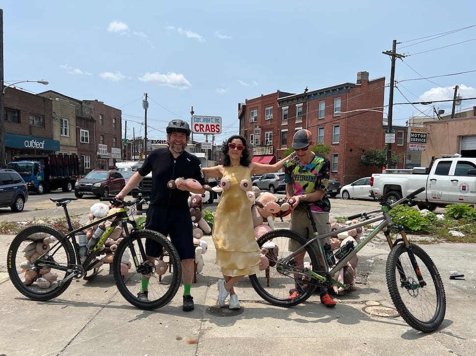 Die Künstlerin Rose Luardo posiert am 15. Juni 2023 mit zwei Radfahrern bei ihrer Kunstinstallation „Boob Garden“ in Süd-Philadelphia.