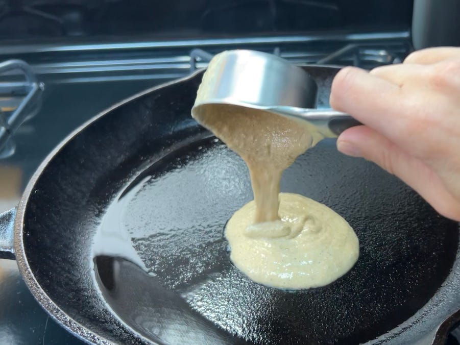 Pfannkuchenteig wird aus einem 1/3 Messbecher in eine heiße Pfanne mit Öl gegossen.