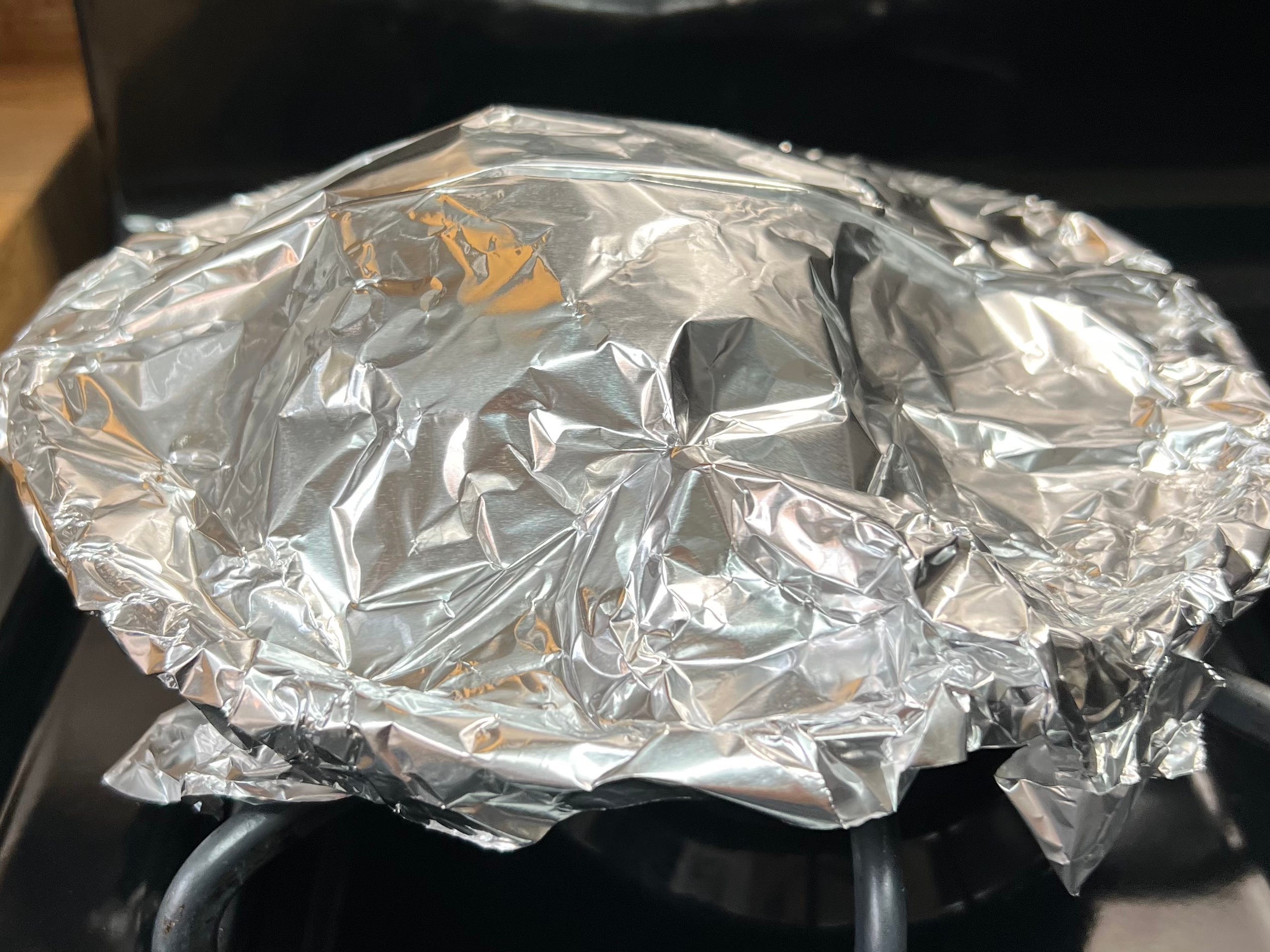Ein Teller mit Pfannkuchen, bedeckt mit Aluminiumfolie.
