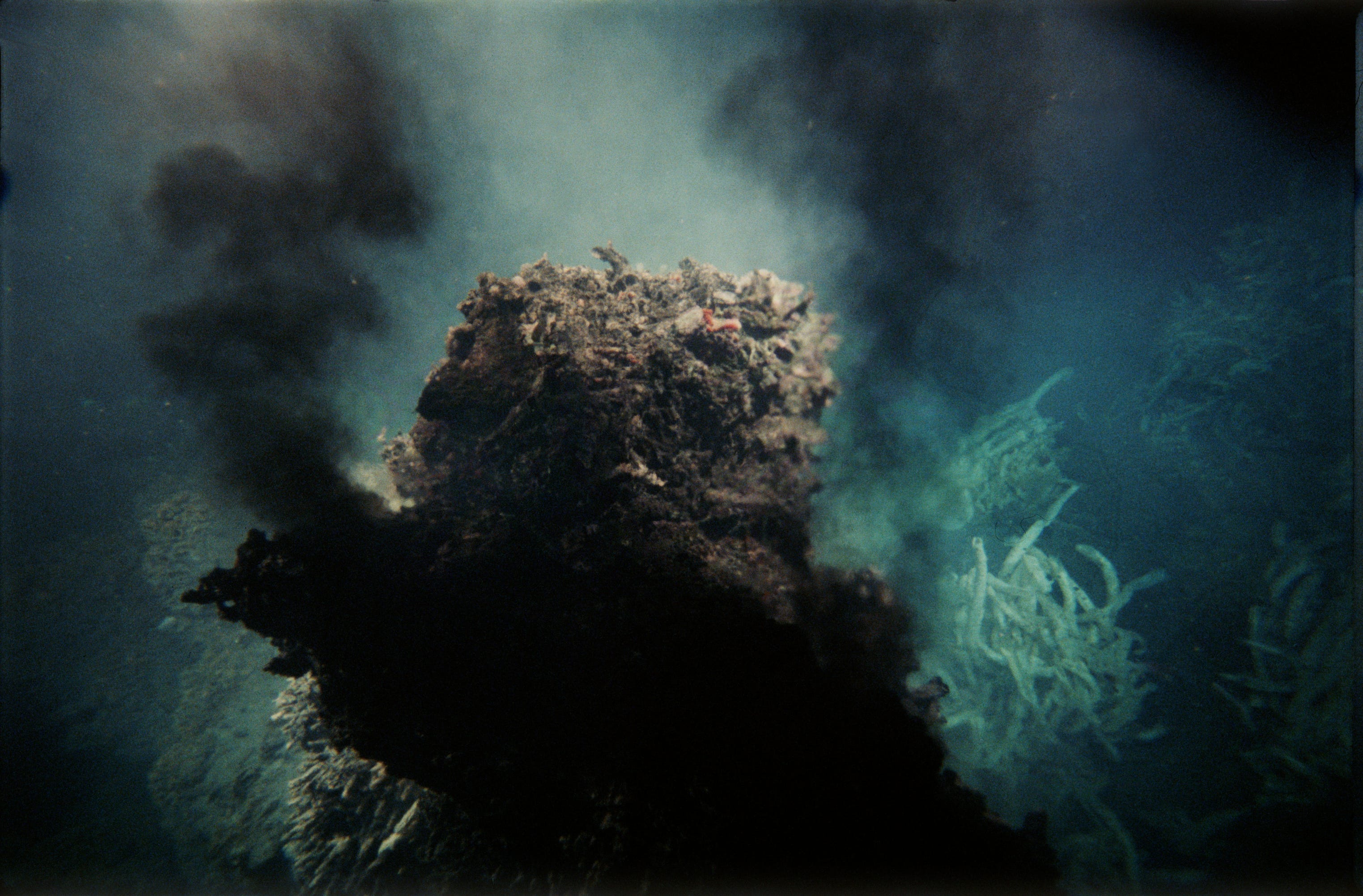 Foto einer Hydrothermalquelle, die schwarzen Rauch ins Wasser spuckt.