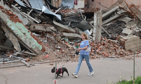 Eine Frau führt letzten Monat mit einem Hund an einem Gebäude vorbei, das von russischem Beschuss in Ochtyrka in der Region Sumy getroffen wurde
