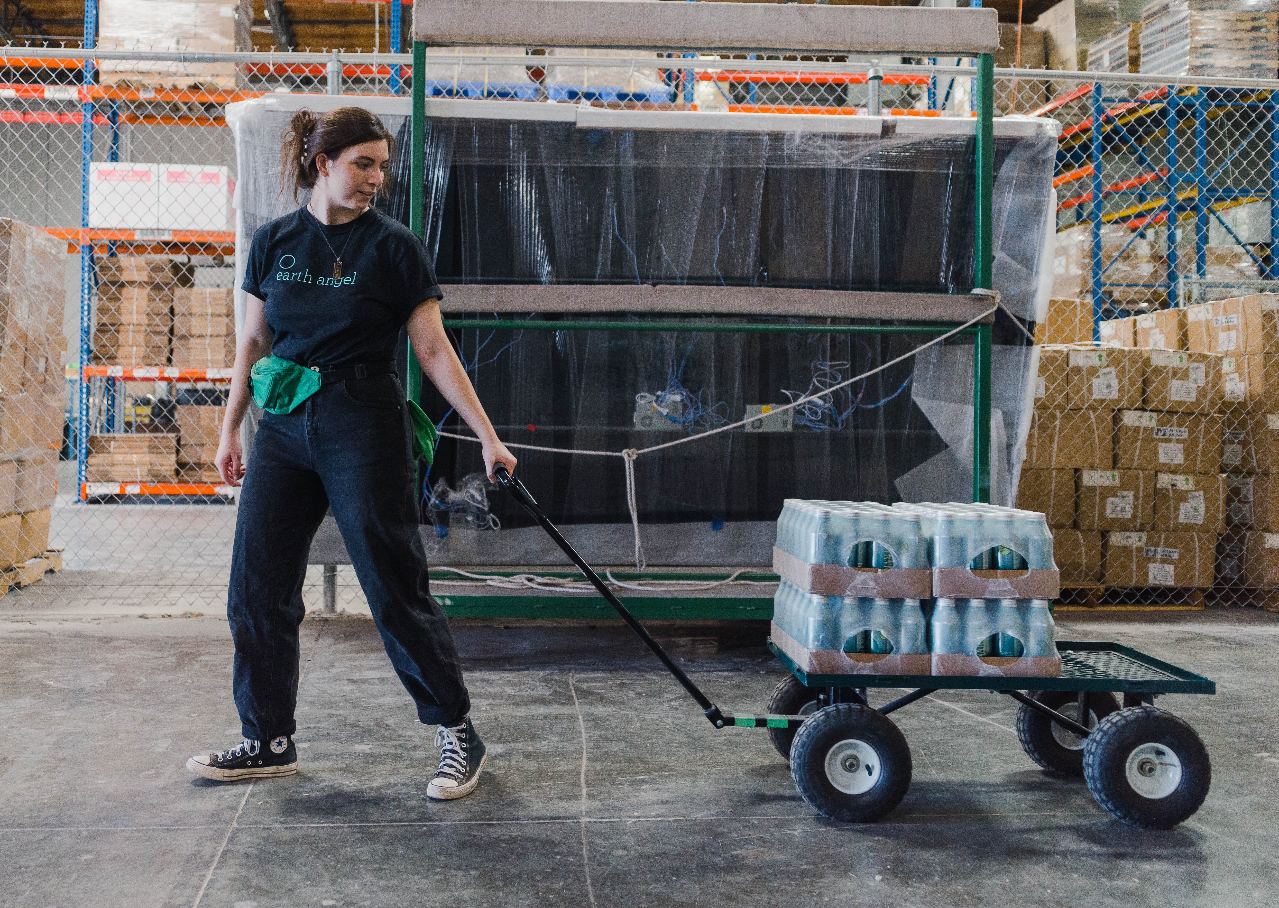 Ein Mitarbeiter von Earth Angel zieht einen Metallkarren mit mit Wasser gefüllten Aluminiumdosen