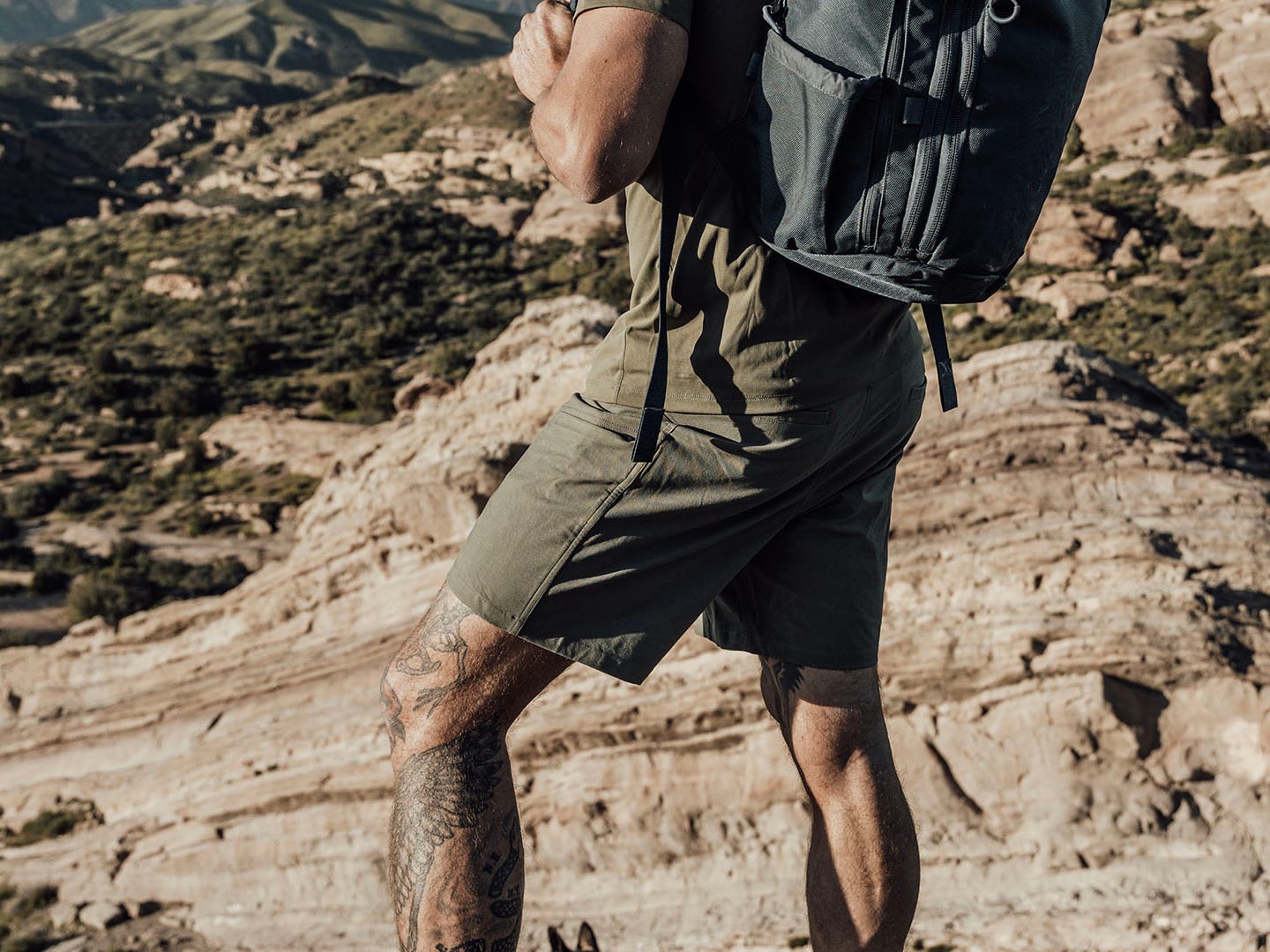 Ein Athlet, der einen Teil seiner Fitnessshorts und einen Rucksack trägt, während er durch bergiges Gelände wandert