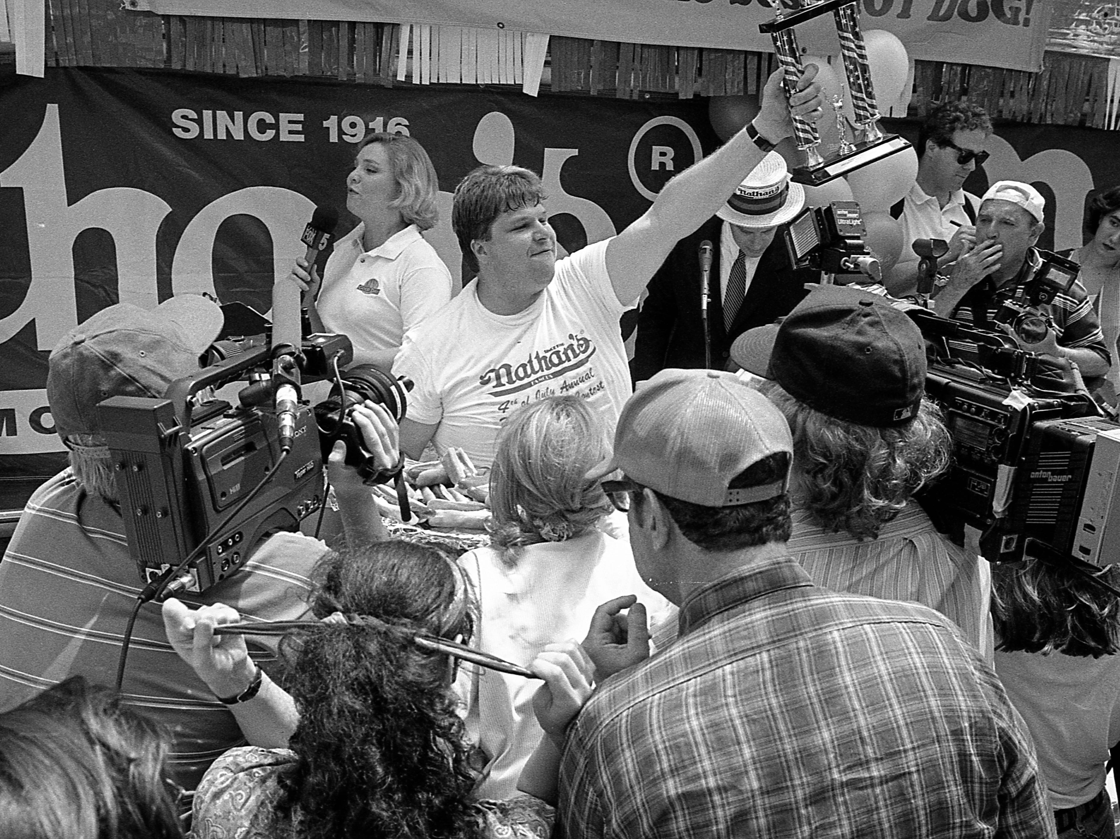 Der amerikanische Leistungsesser Edward Krachie hält eine Trophäe in seinen Händen, als er seinen Sieg beim Nathan's Hot Dog Eating Contest 1995 auf Coney Island feiert