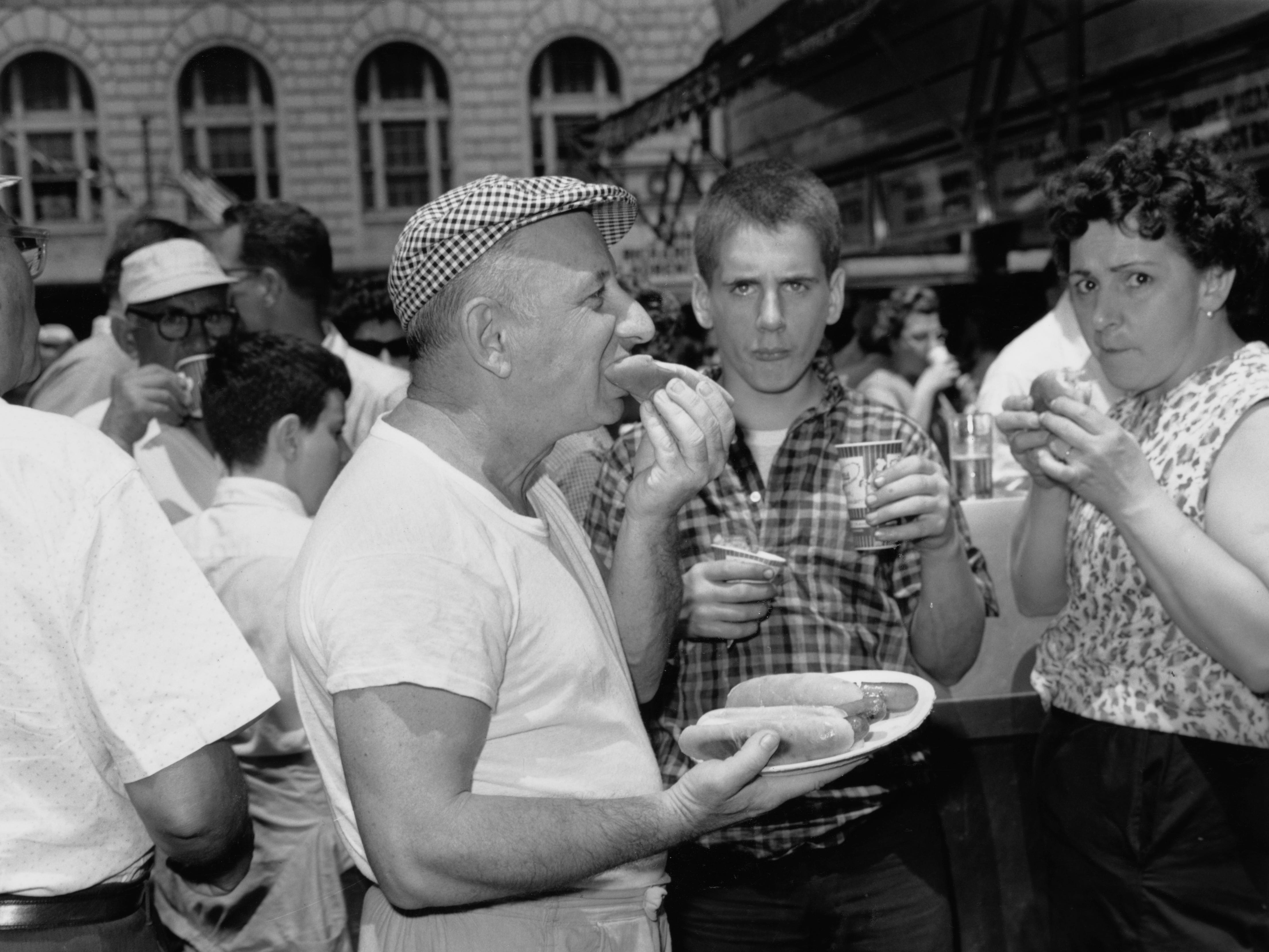 Ein Mann isst am 4. Juli 1961 Hotdogs bei Nathan's Famous auf Coney Island