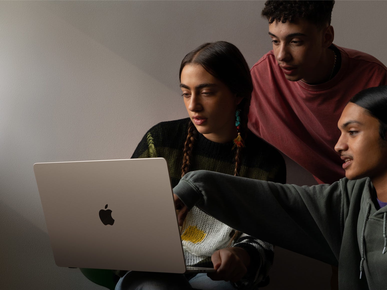 Drei Personen betrachten ein Apple MacBook Air 15-Zoll-Notebook