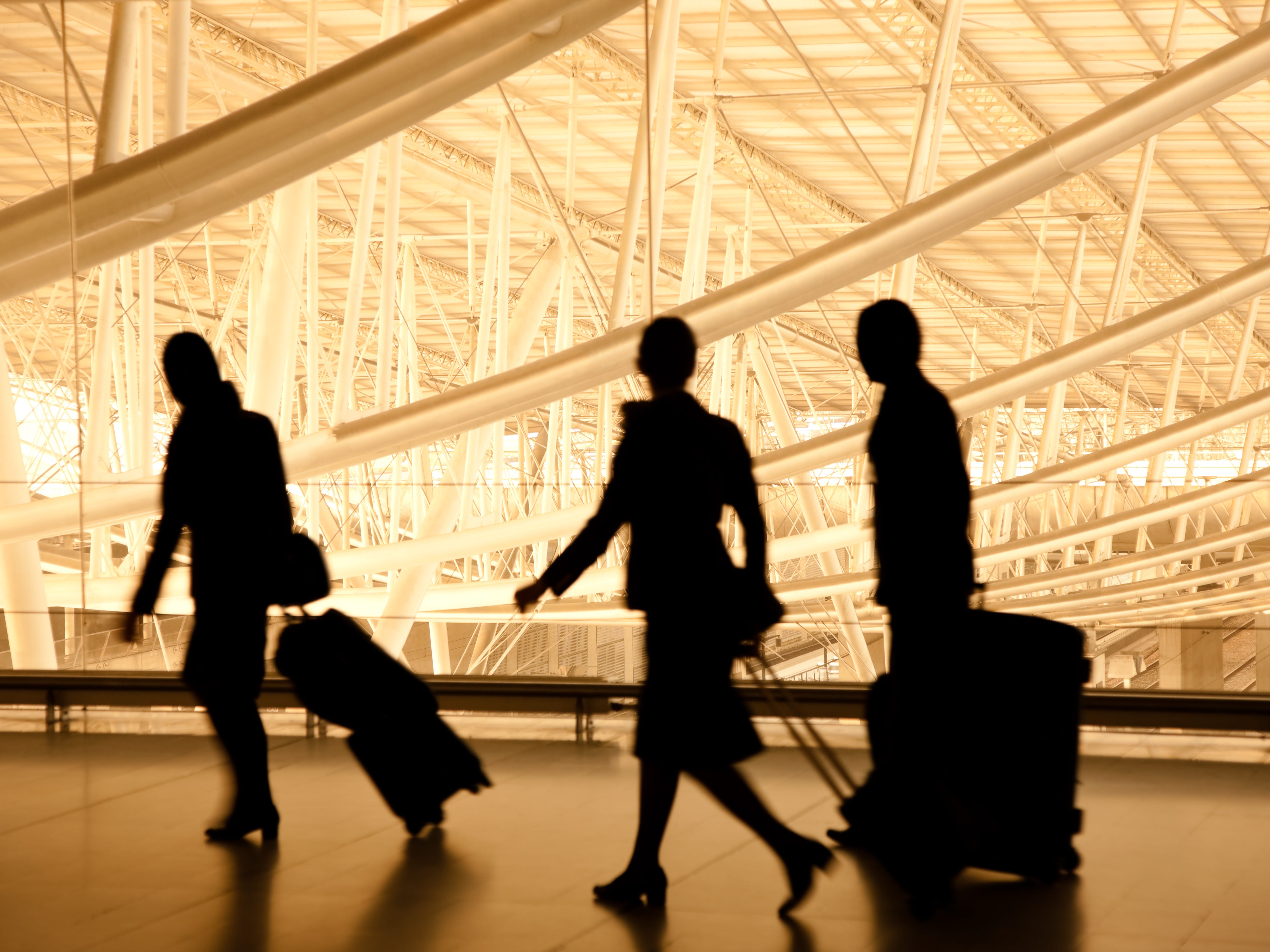Silhouette von drei Reisenden im Flughafen mit Gepäck