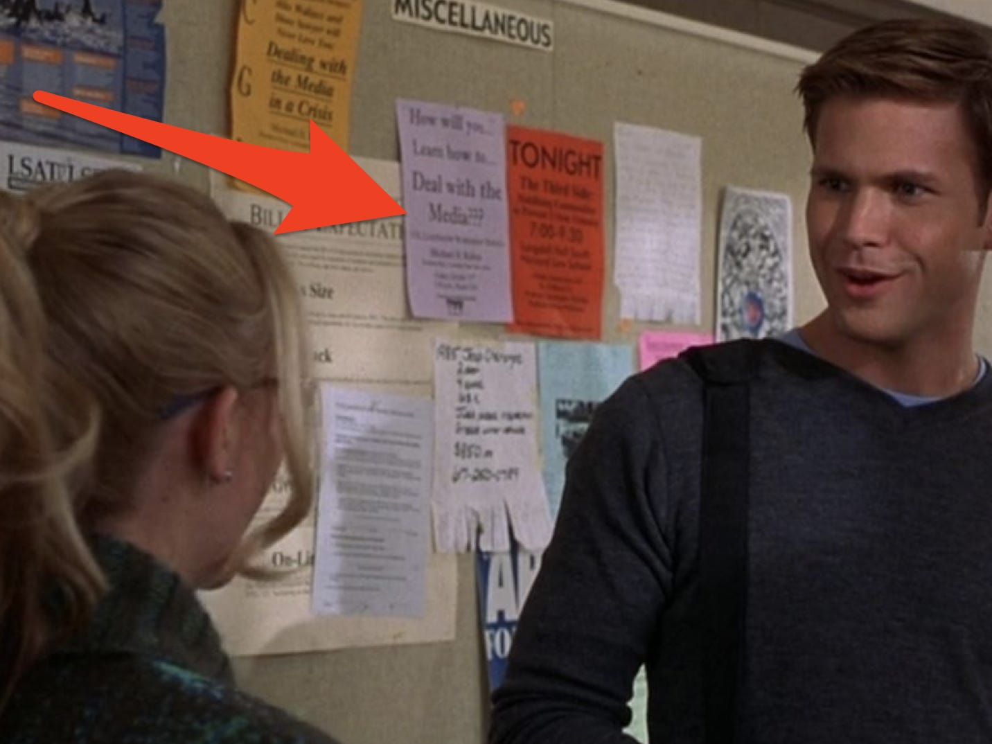 Roter Pfeil zeigt auf Flyer auf einer Pinnwand hinter Elle und Warren in einer Szene aus „Legally Blonde“.