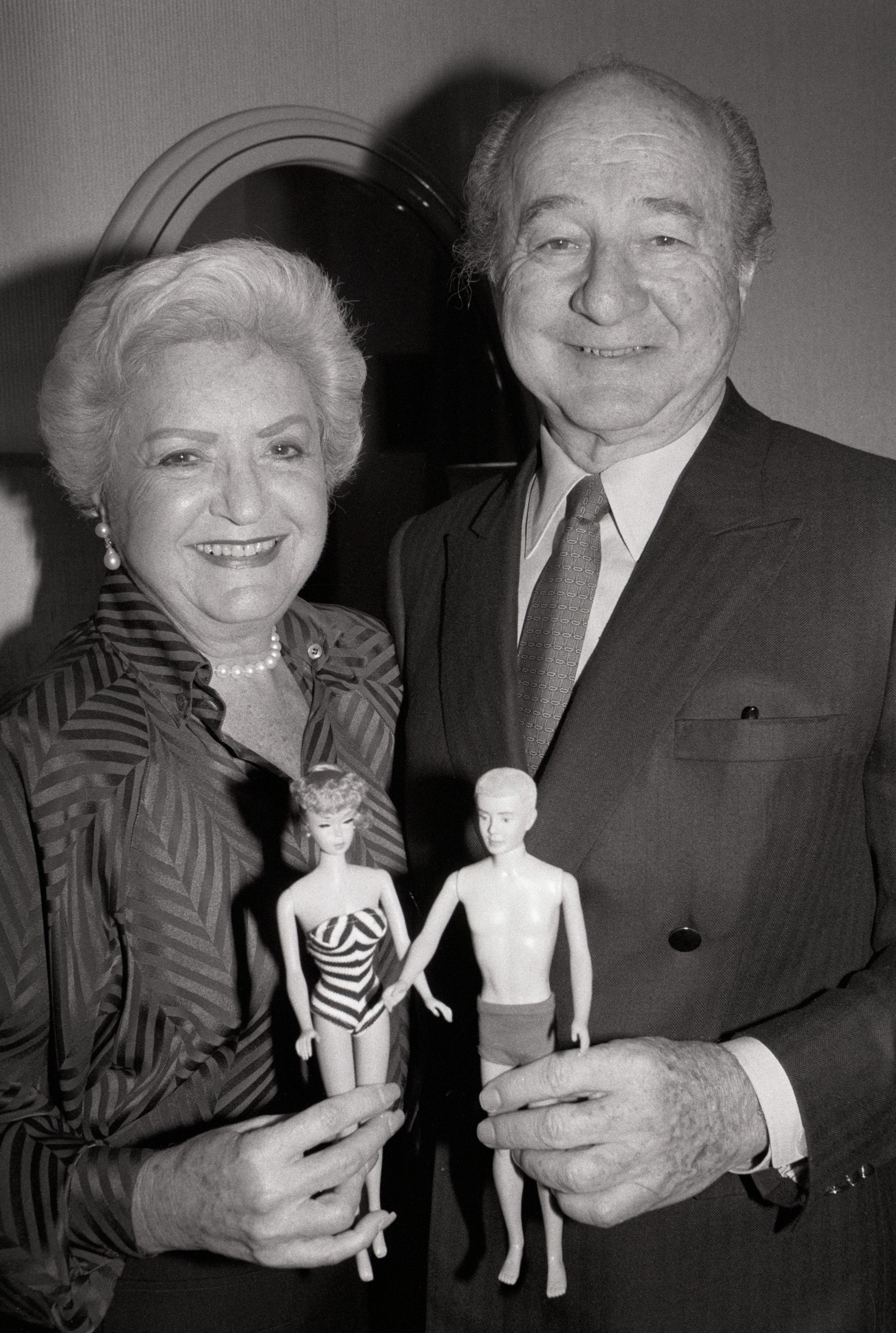 Ein Porträt von Ruth und Elliott Handler, dem Paar, das 1959 die Barbie-Puppe vorstellte, mit einer Barbie- und Ken-Puppe in der Hand.