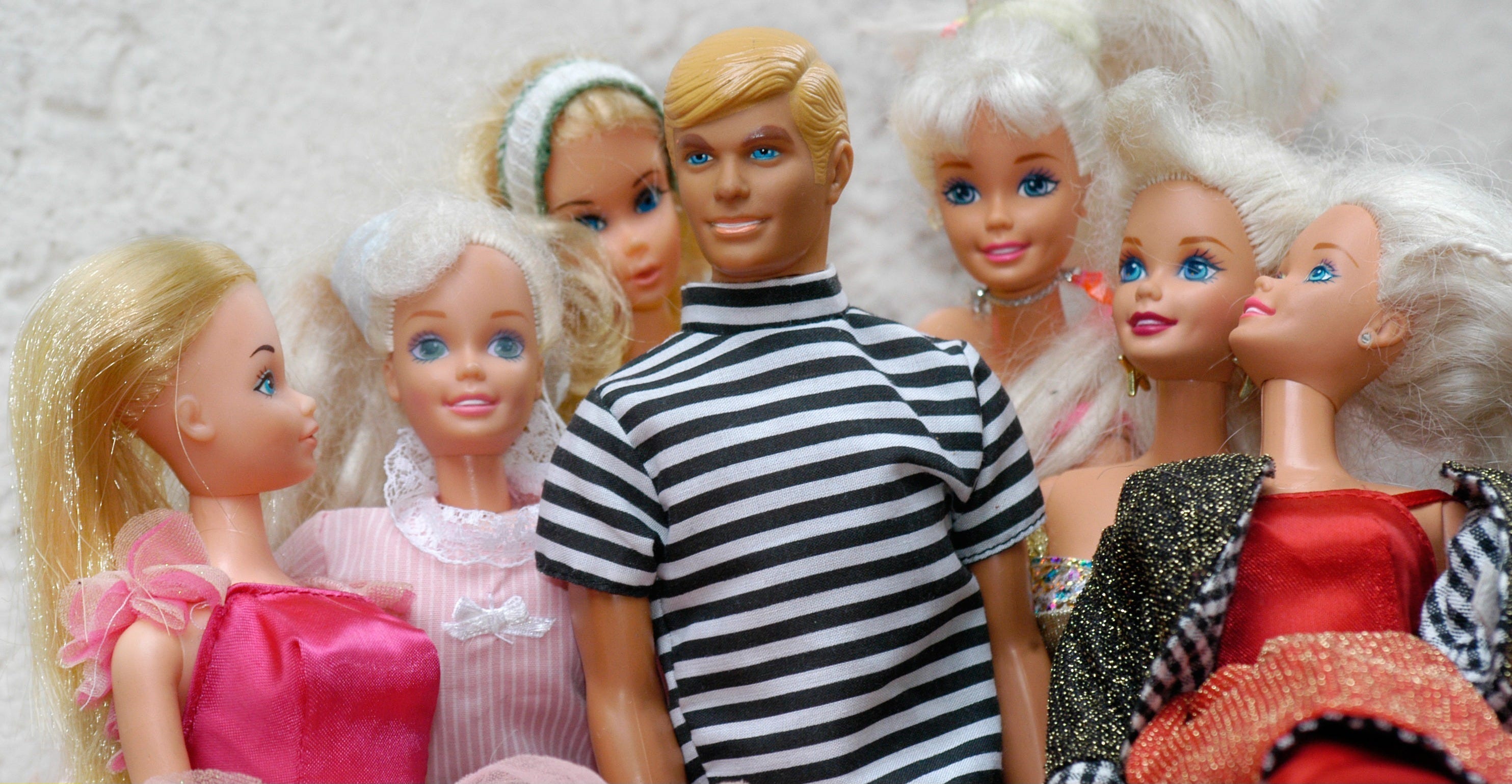 Eine Ken-Puppe, umgeben von sechs bezaubernden Barbies