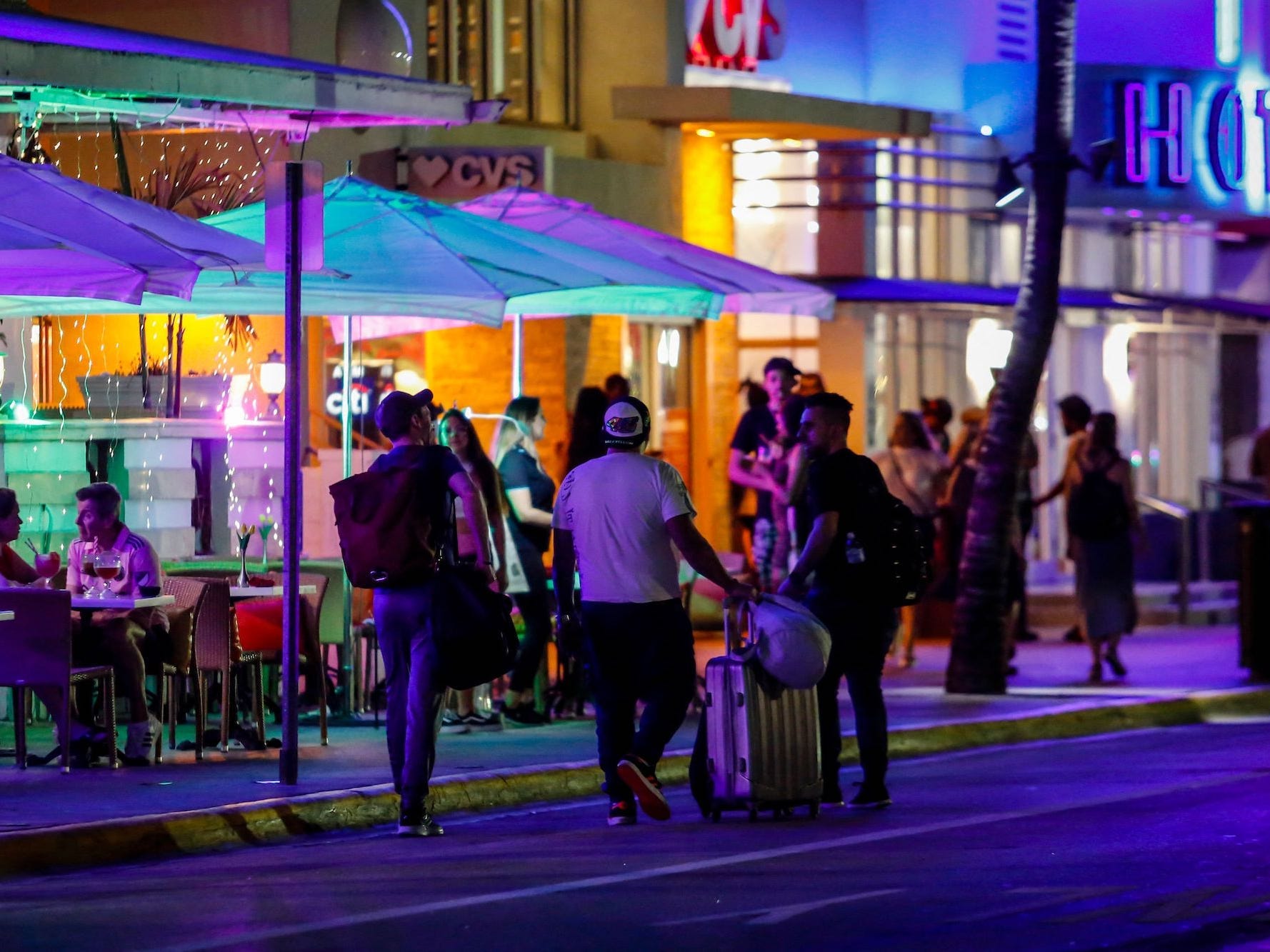 Spring Breaker laufen nachts in Miami eine Straße entlang.