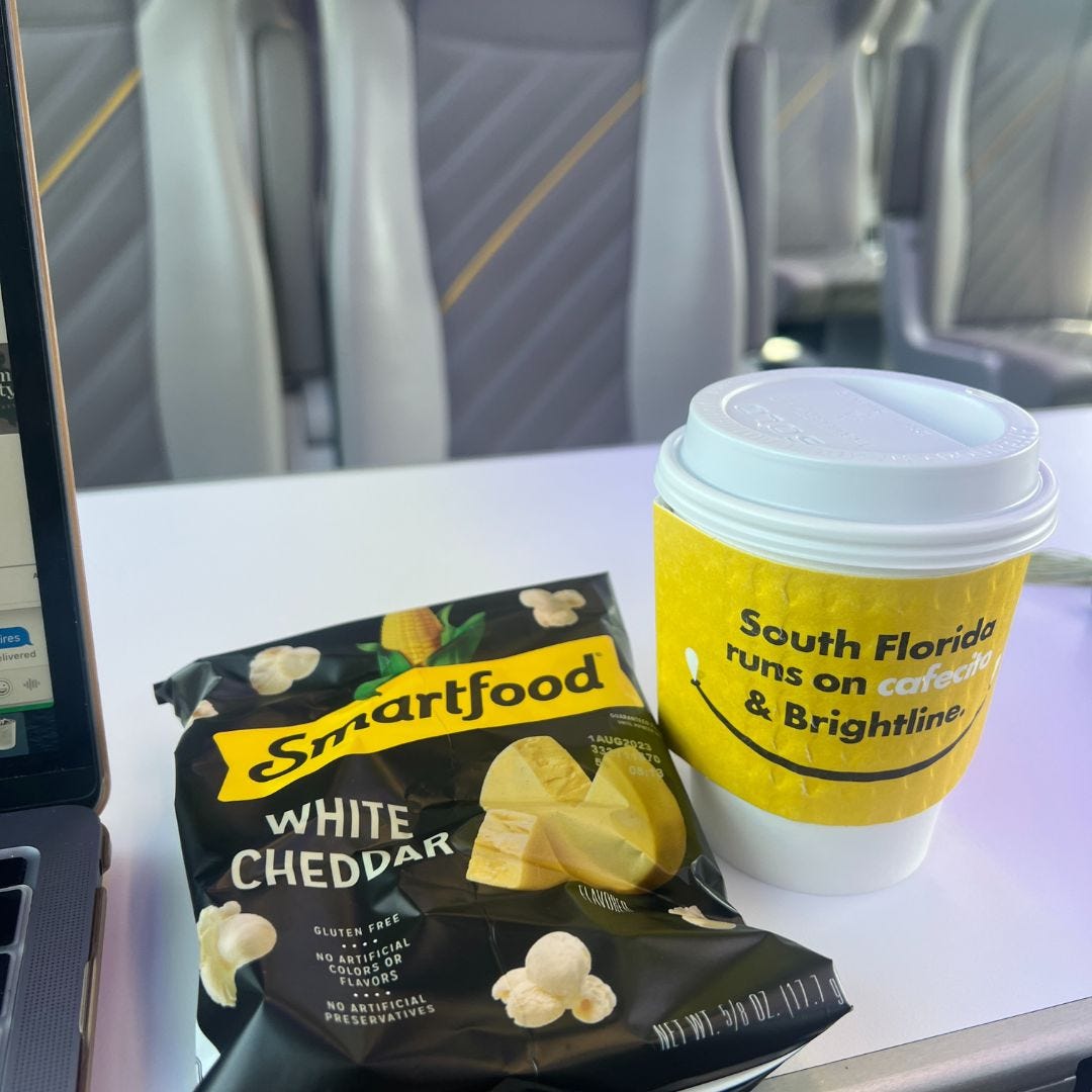 Smartfood-Popcorn und Kaffee mit gelber Hülle auf dem Tabletttisch im Zug