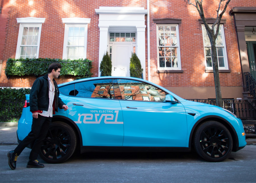 Ein Kunde begrüßt eine Fahrt in einem der puderblauen Model Y-Elektrofahrzeuge von Revel.