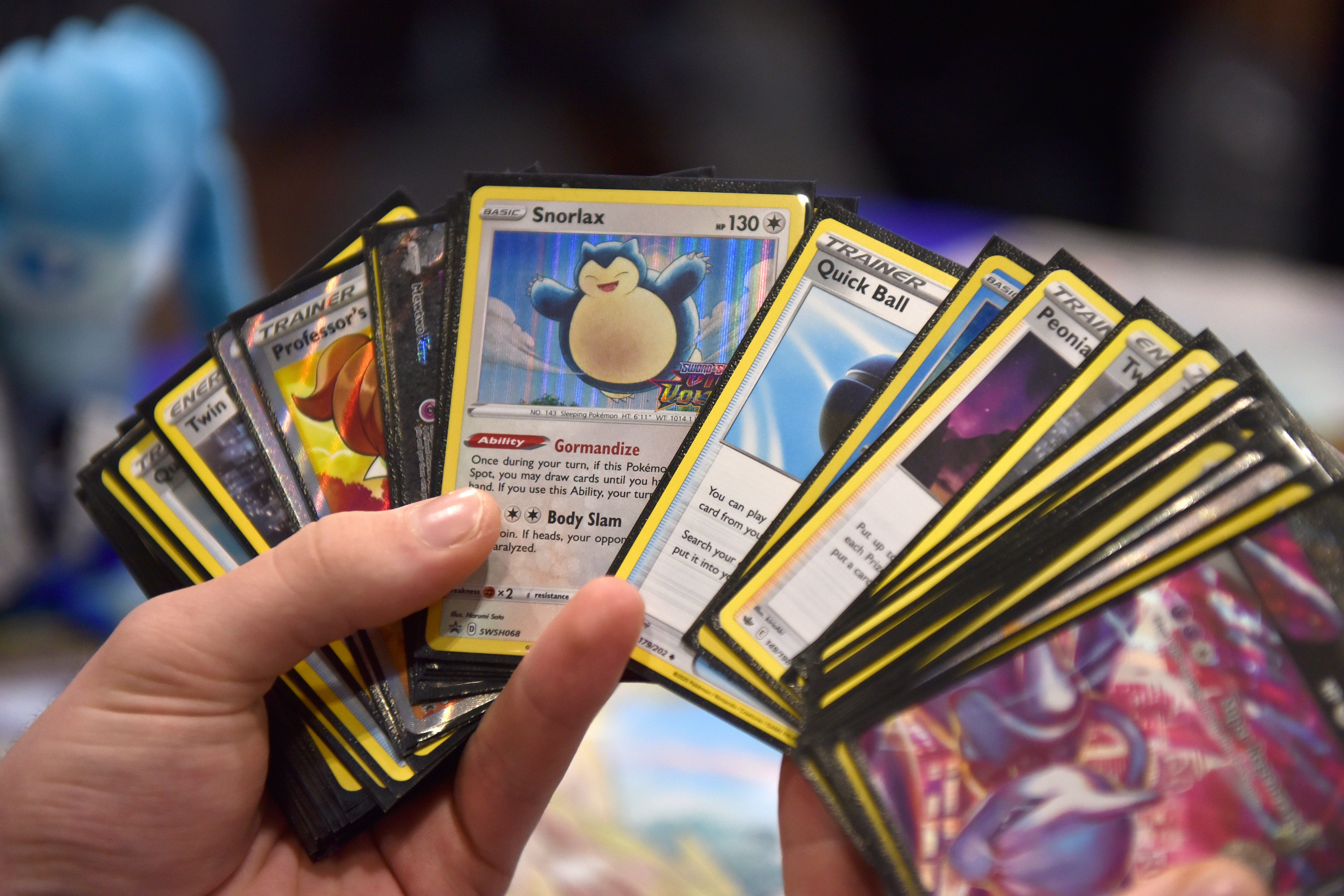 Pokémon-Karten, darunter ein Relaxo, sind ausgebreitet in einer Hand zu sehen.