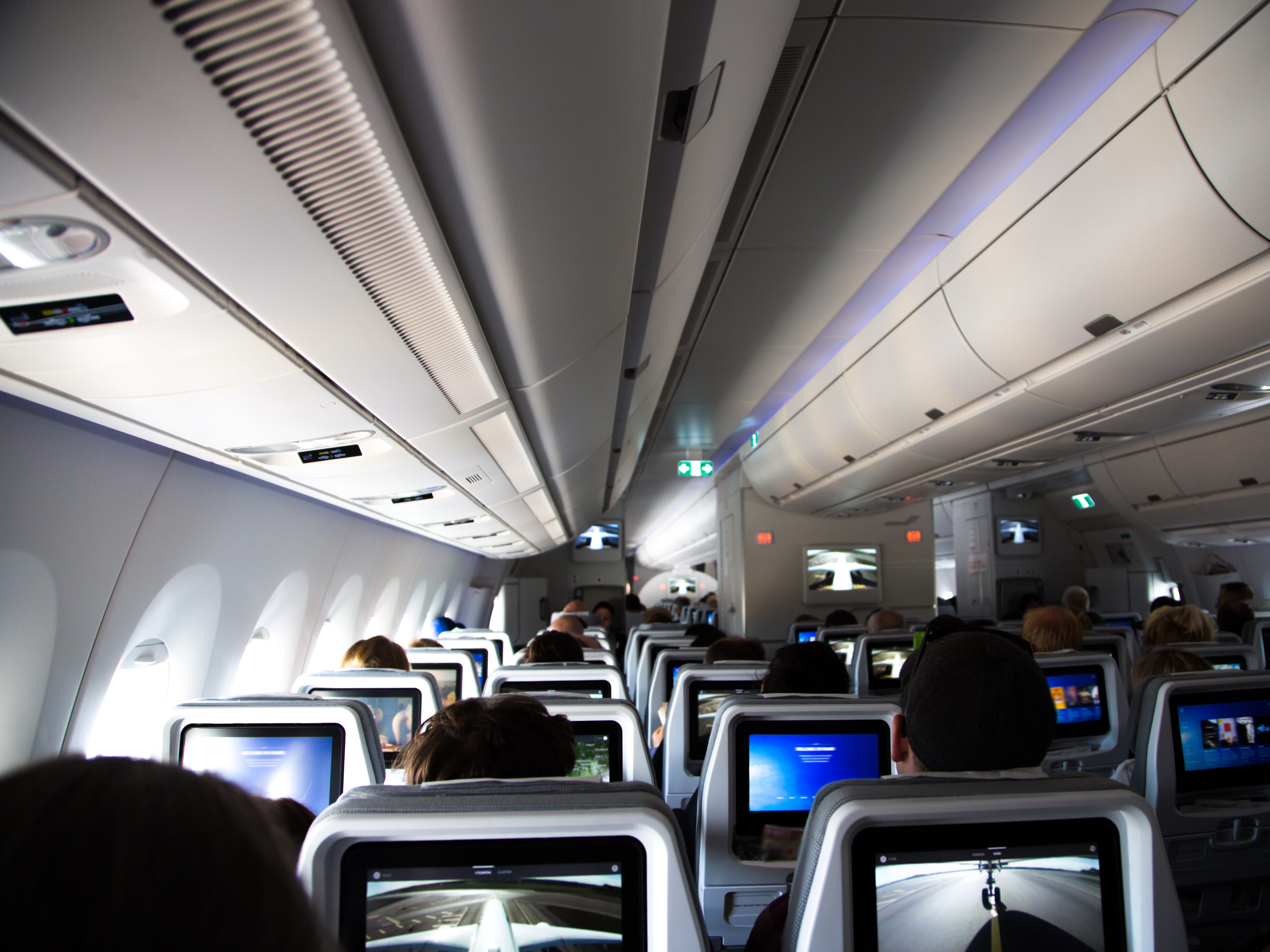 Im Inneren eines neuen Langstreckenflugzeugs mit Passagieren, die während eines Langstreckenflugs sitzen und sich ausruhen, mit einem Foto, das von der Rückseite des Flugzeugs aus aufgenommen wurde