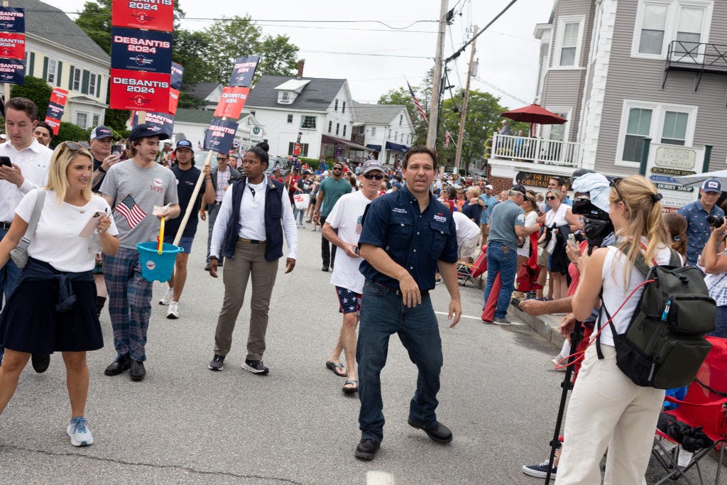 Gouverneur Ron DeSantis steht während einer Parade mitten auf der Straße.