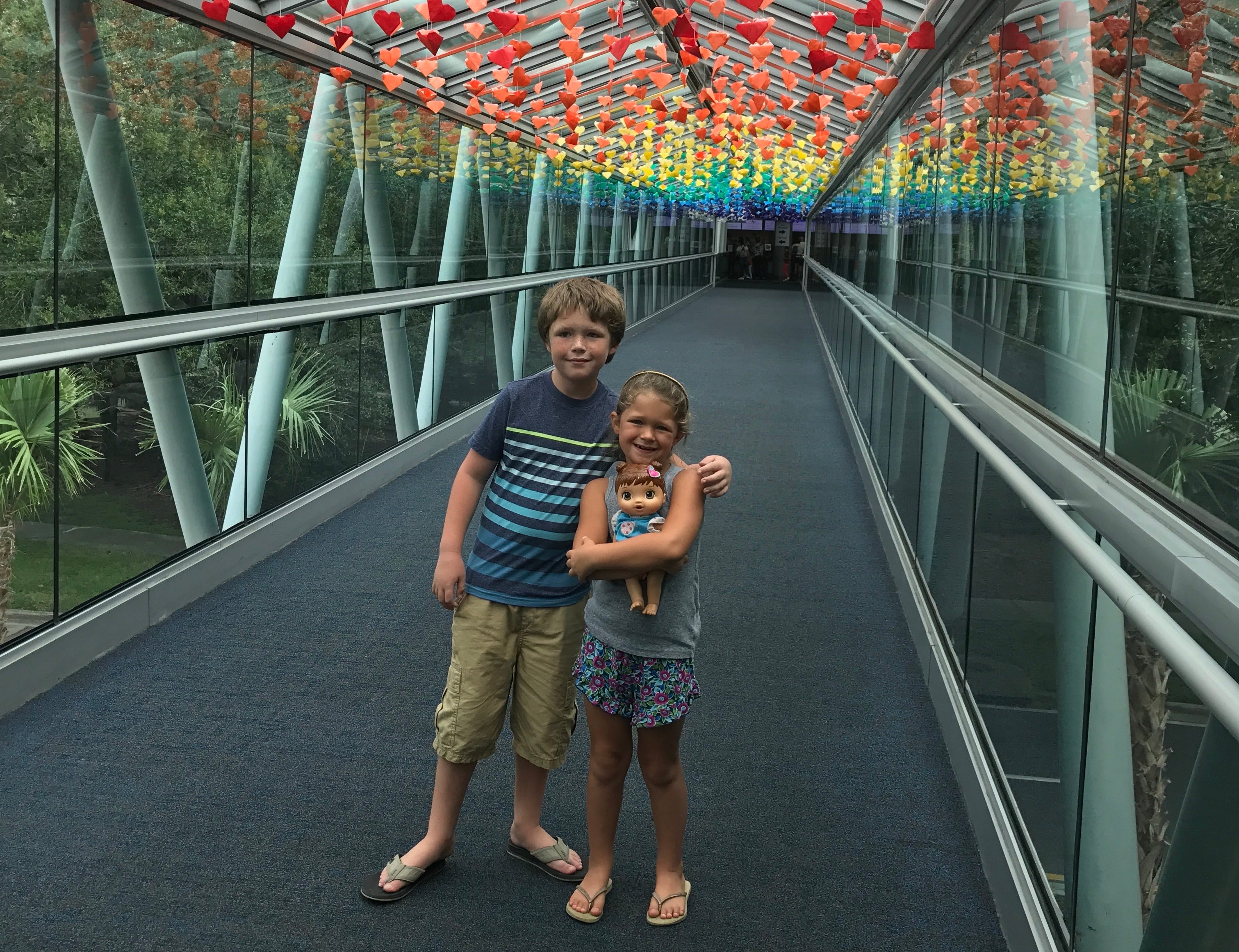 Zwei Kinder auf einem Gehweg unter einer Regenbogendecke