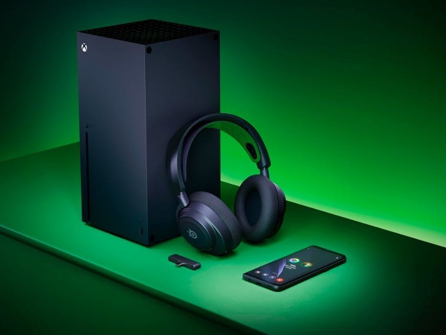 Ein SteelSeries Arctis Nova 7X-Headset, das auf einer Xbox Series X neben einem Smartphone lehnt.