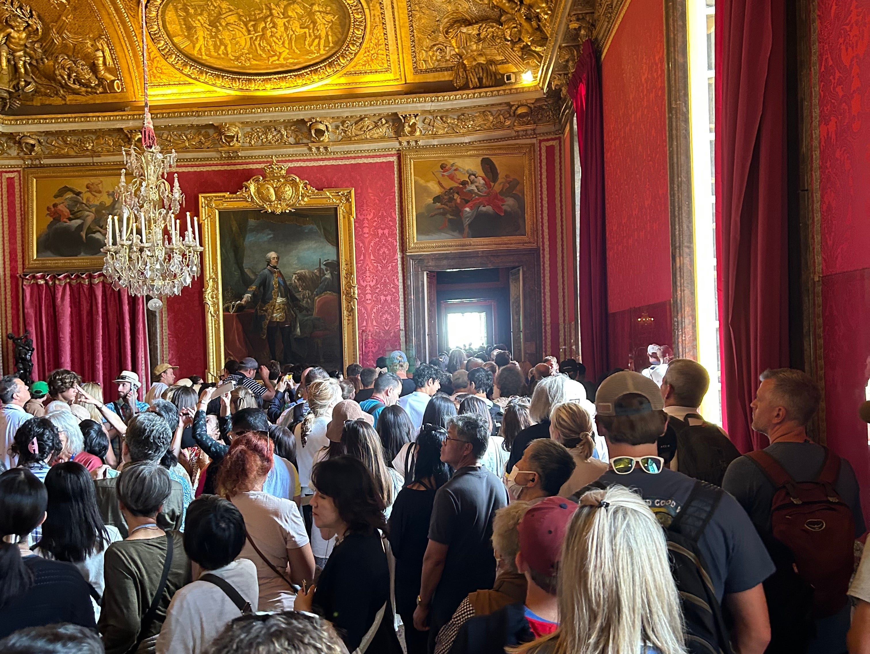 Touristen stehen in einem Raum im Schloss Versailles.
