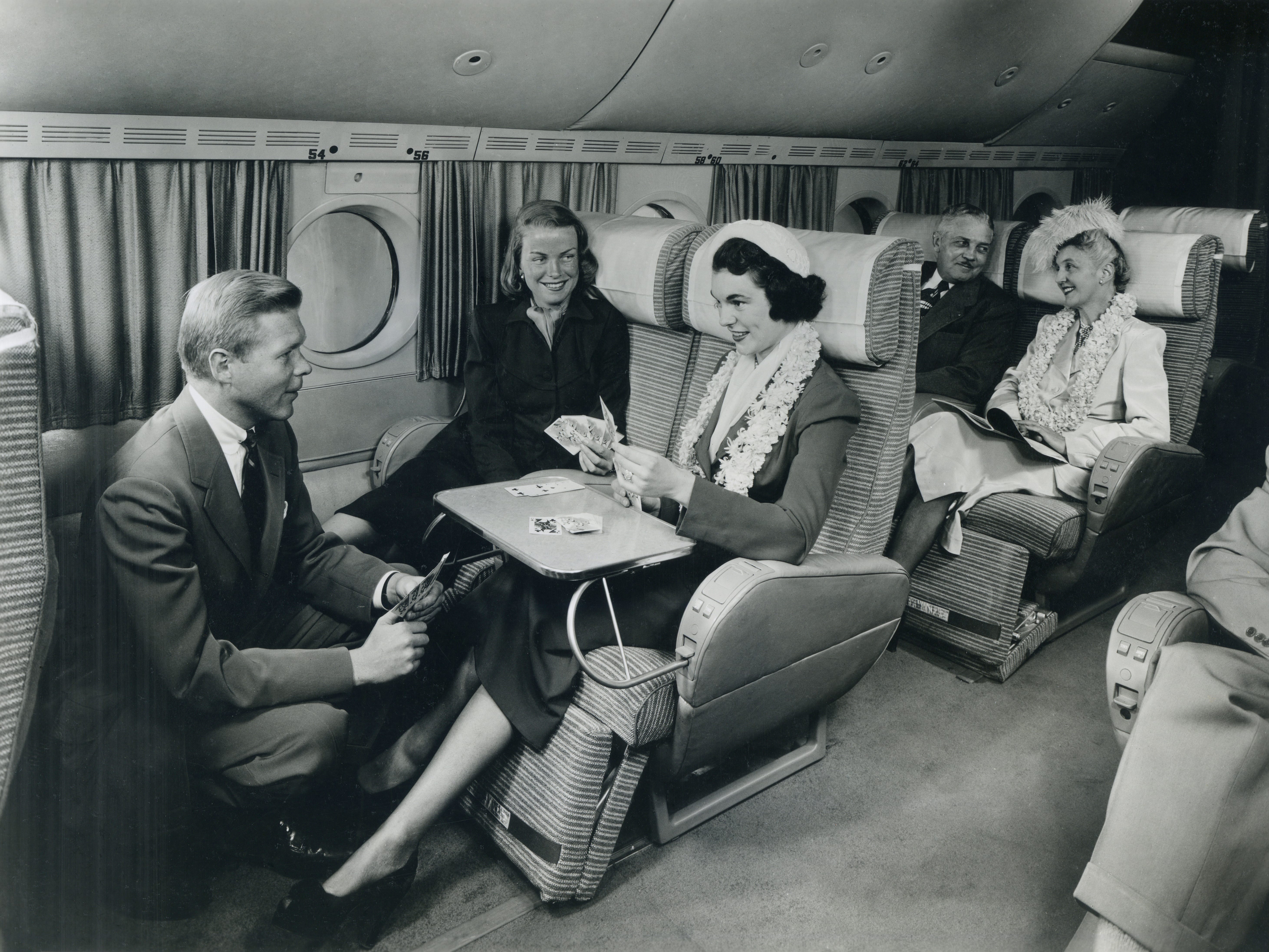 Flugpassagiere spielen Karten und unterhalten sich in einem geräumigen Verkehrsflugzeug, etwa 1949