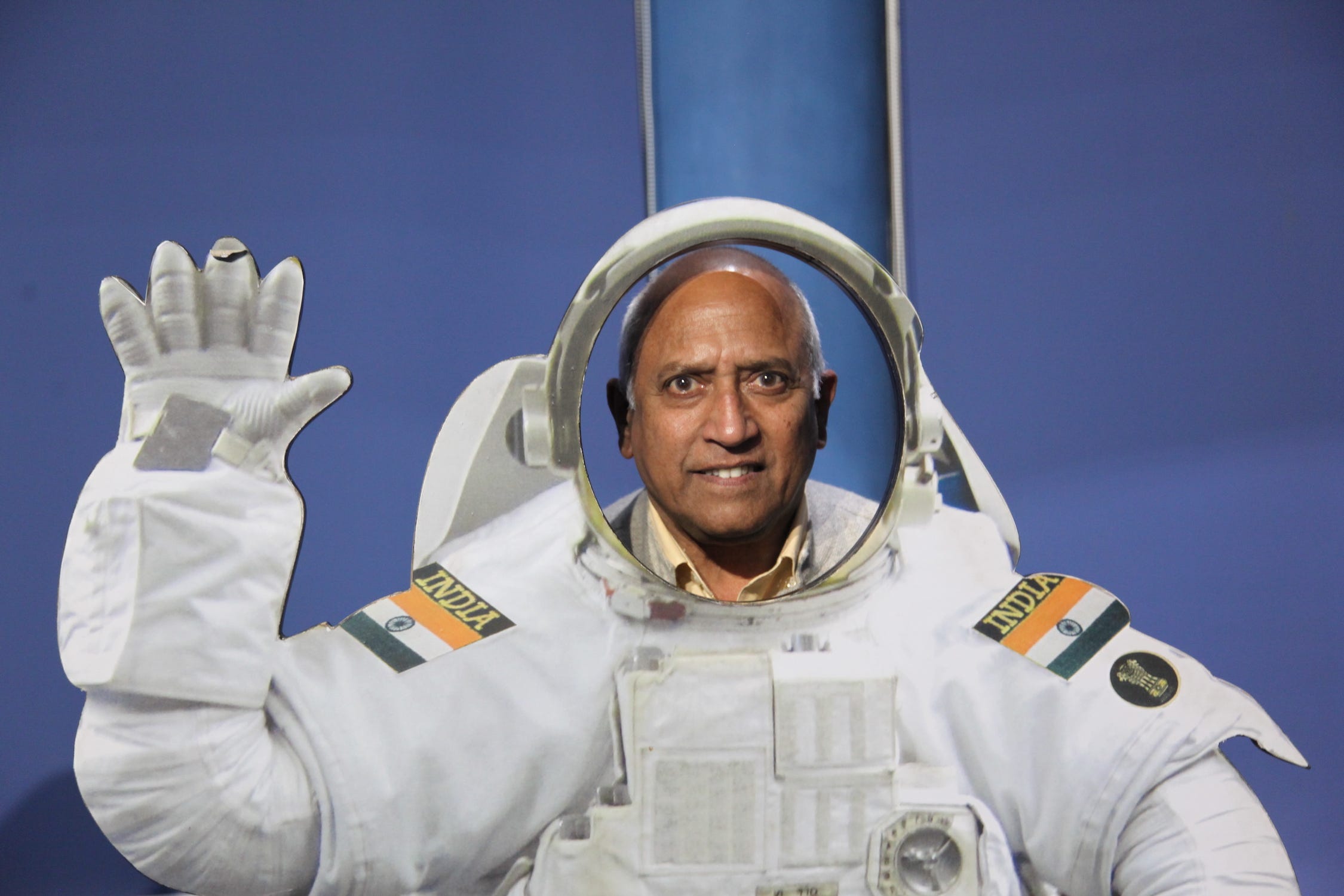 Mann posiert in weißer, wehender Astronautenuniform mit Aufnähern der indischen Flagge auf jeder Schulter