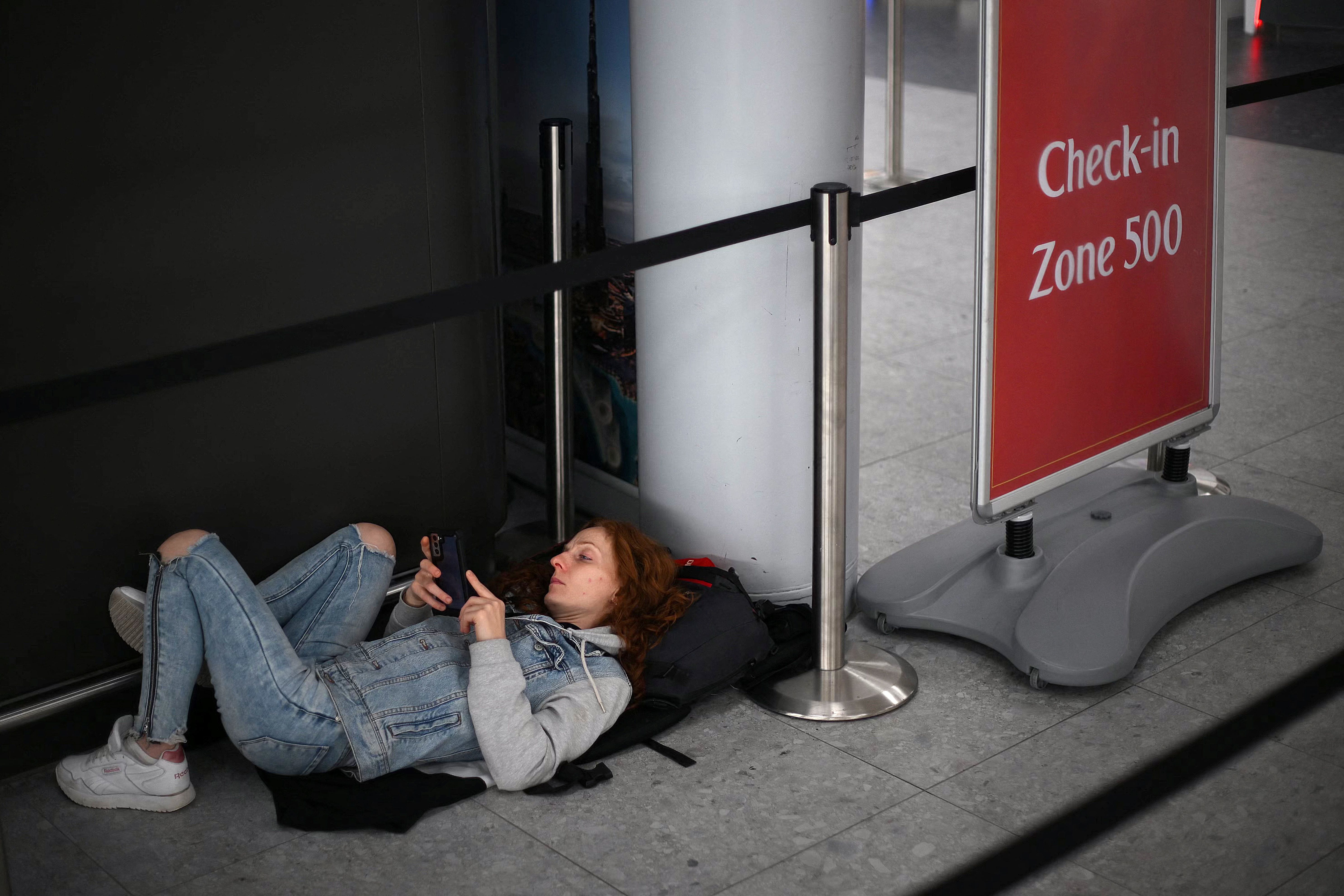Ein Passagier liegt auf dem Boden neben einem Check-in-Schild am Flughafen Stansted.