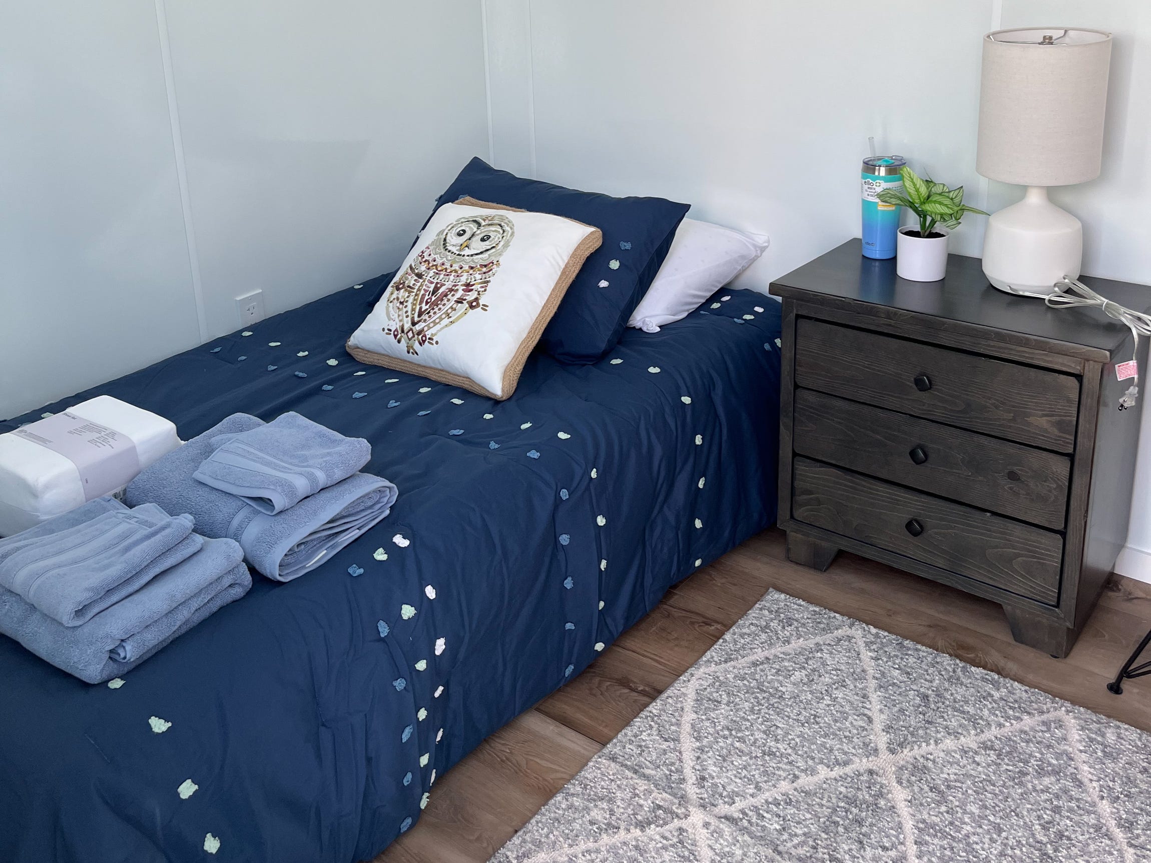 Ein Bett und ein Nachttisch in einem Tiny Home am Standort Santa Barbara von DignityMoves