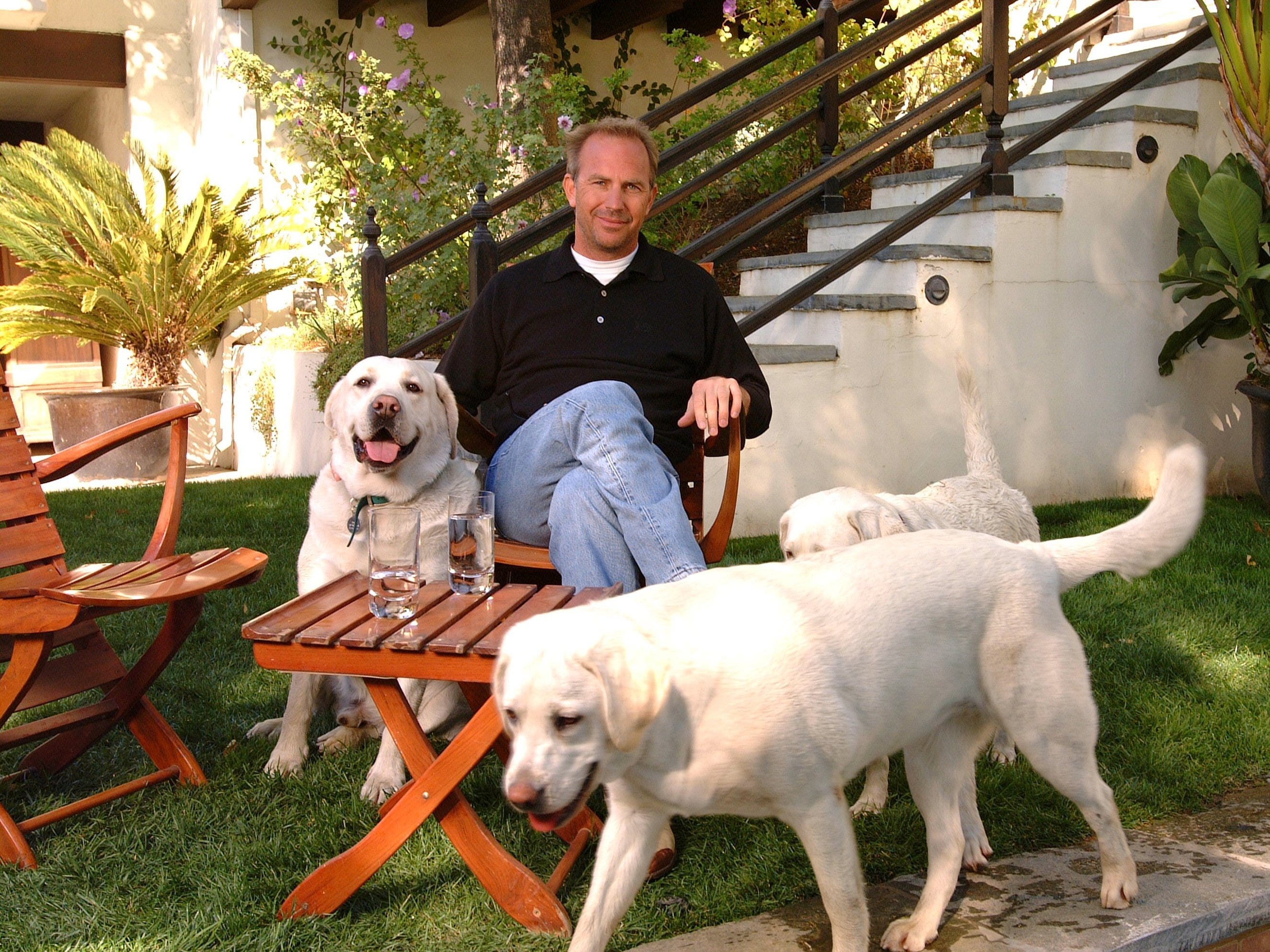 Kevin Costner sitzt 2002 mit seinen Hunden im Garten eines seiner Häuser.
