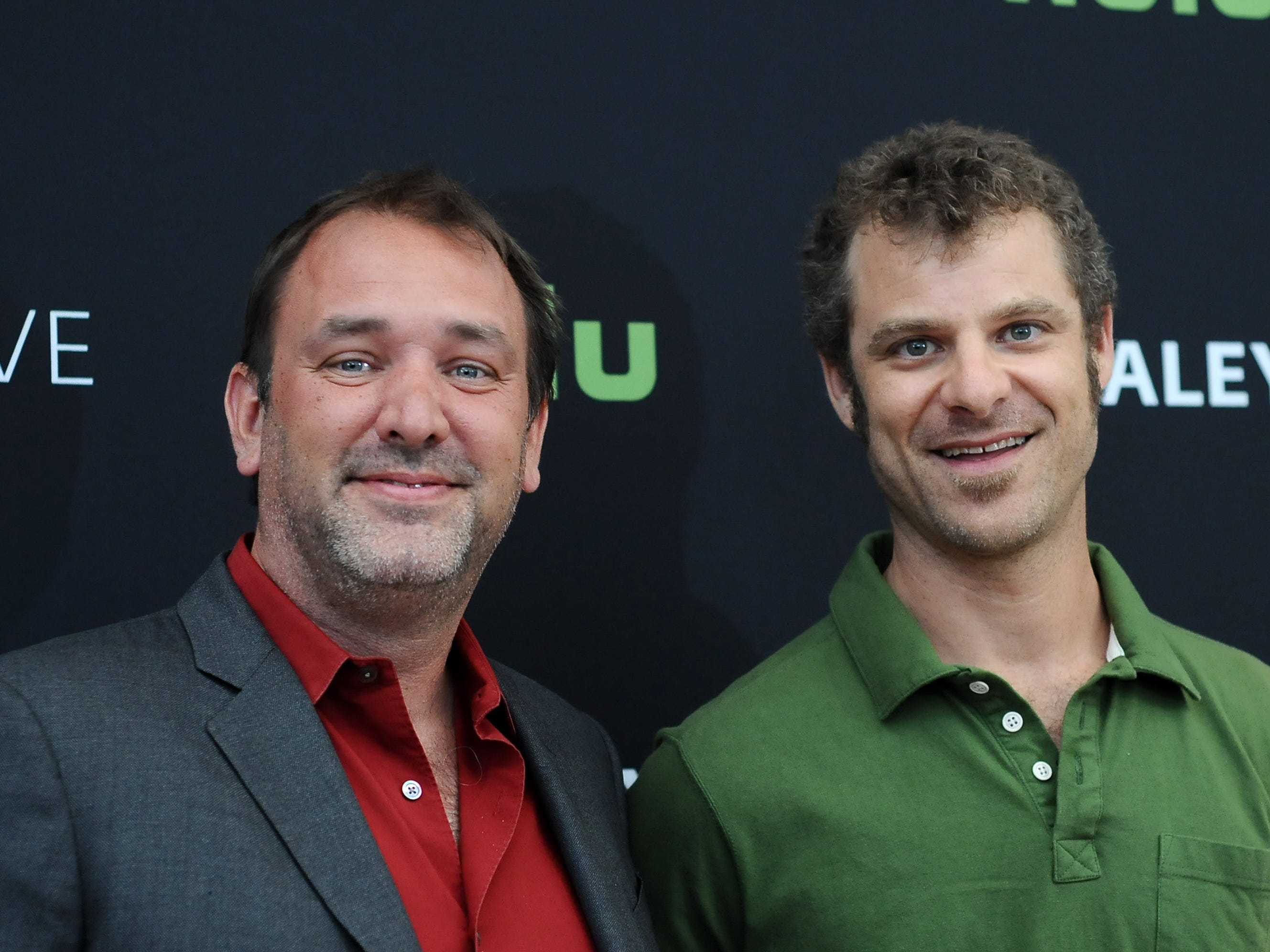 Trey Parker, der einen schwarzen Blazer und ein rotes Button-Down-Shirt trägt, und Matt Stone, der ein grünes Poloshirt trägt, stehen zusammen.
