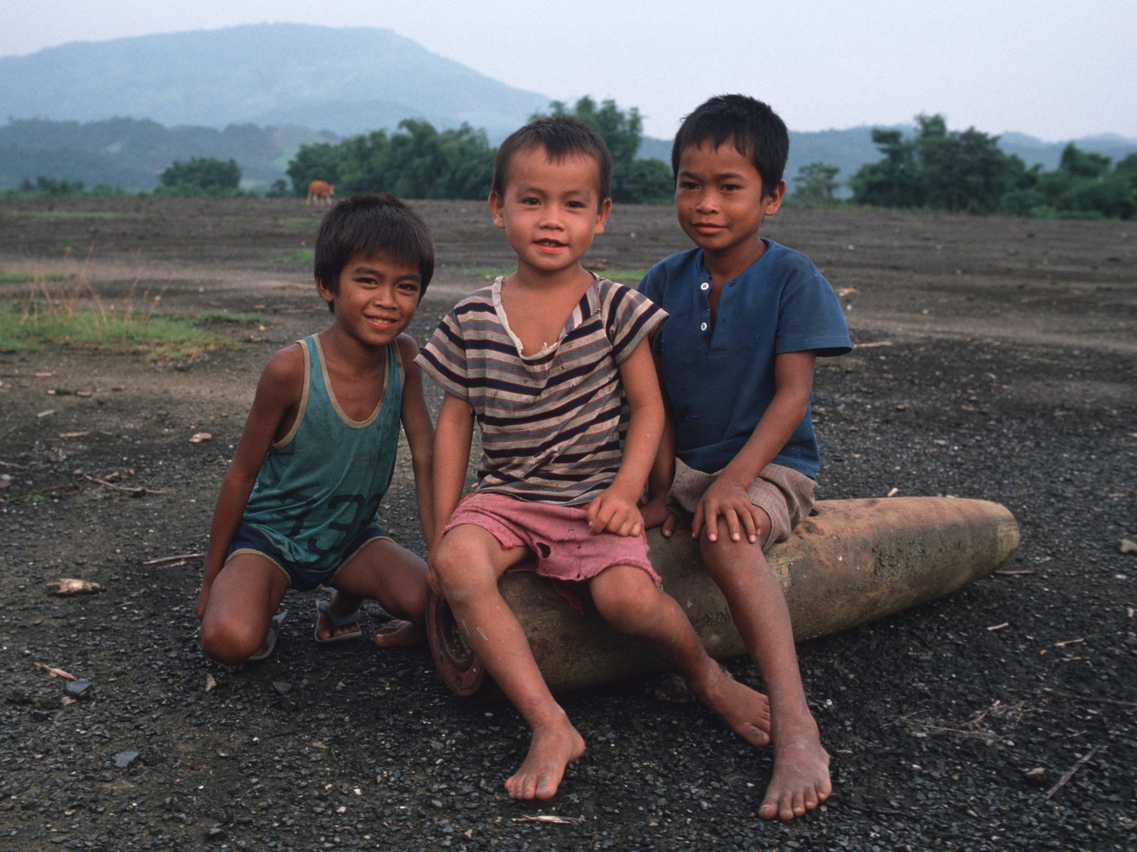 Kinder in Vang Vieng, Laos, posieren für ein Foto, während sie auf einer entschärften US-Bombe sitzen, die während des Vietnamkriegs abgeworfen wurde.