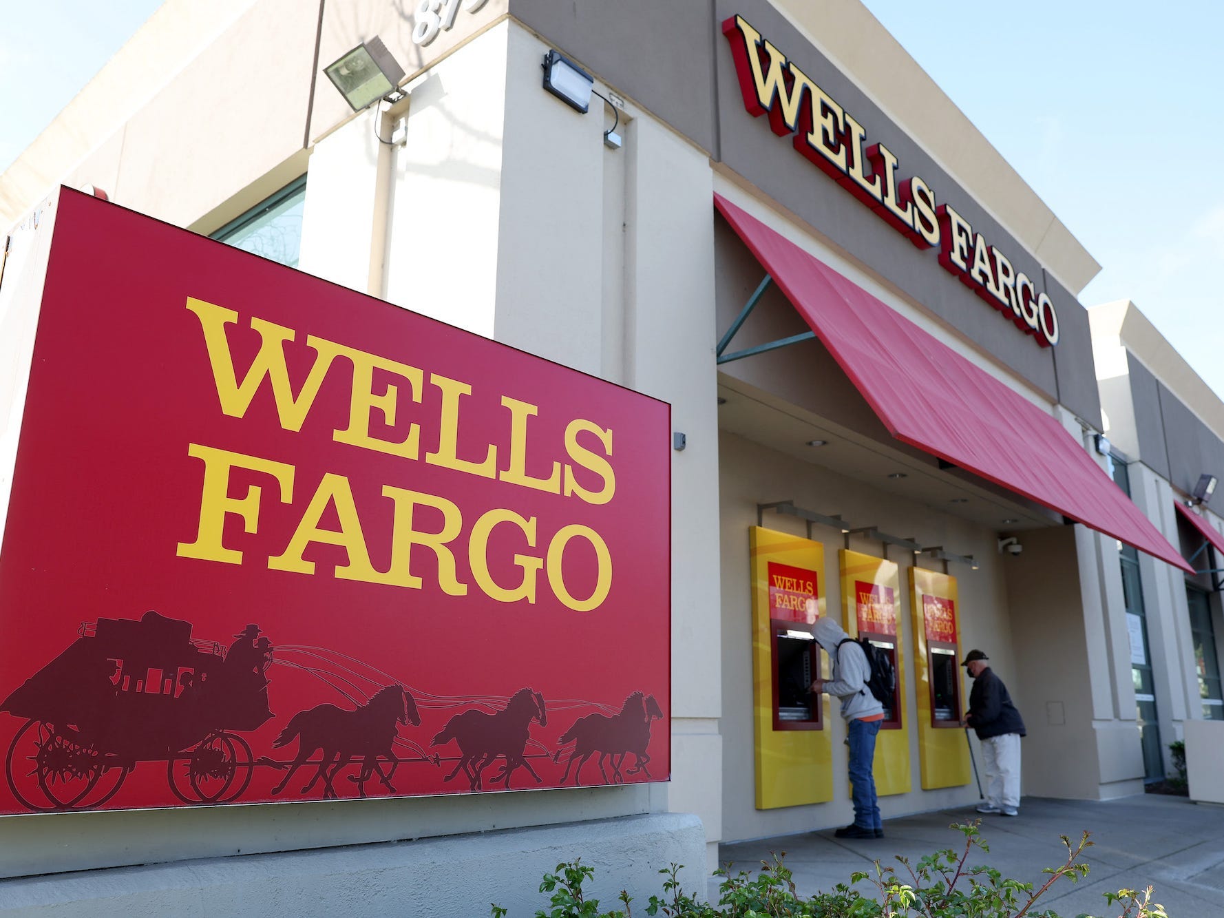 Zwei Personen benutzen verschiedene Geldautomaten an einem Standort in Wells Fargo