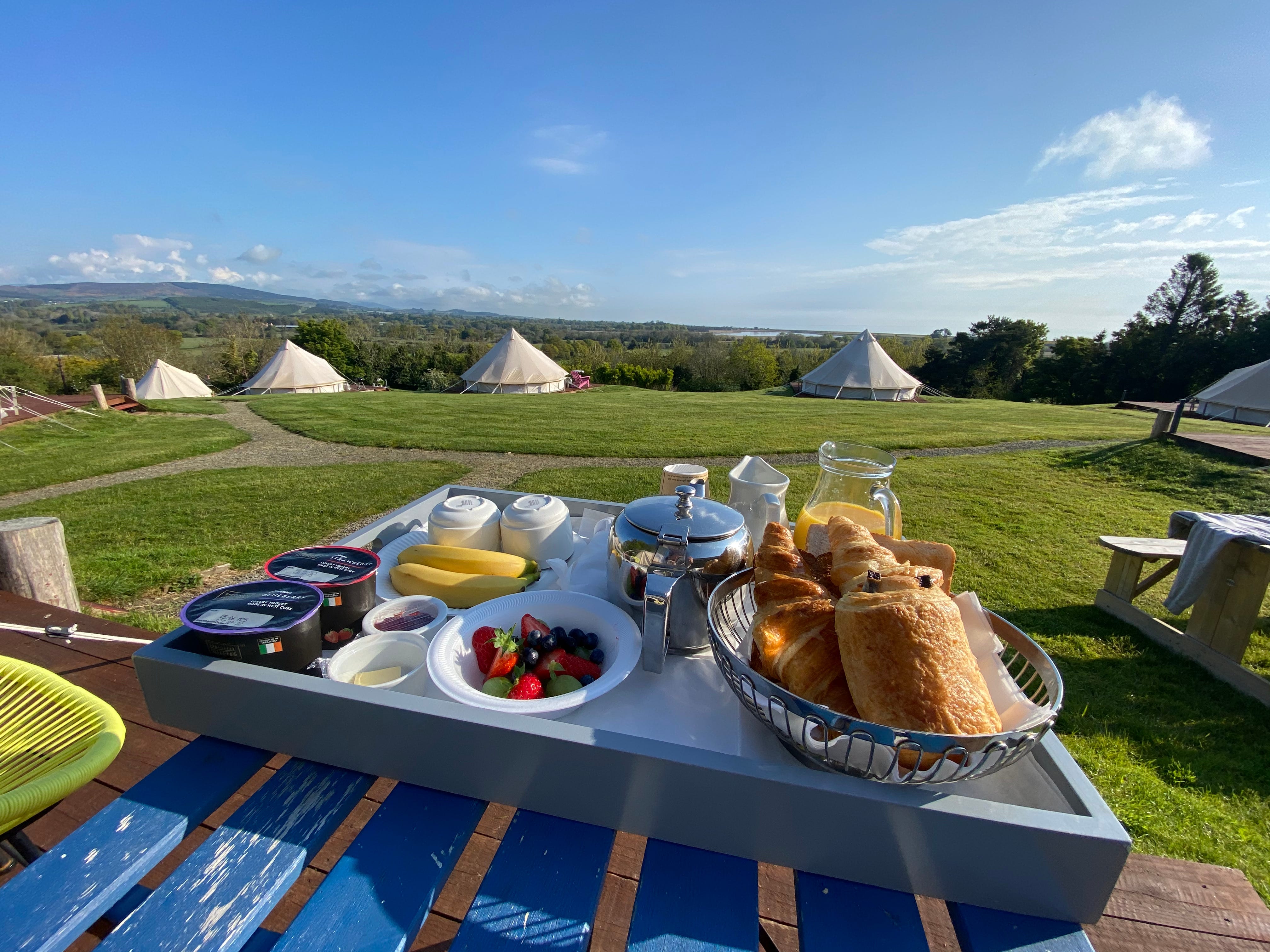 Frühstückstablett mit Blick auf Zelte auf einem Campingausflug